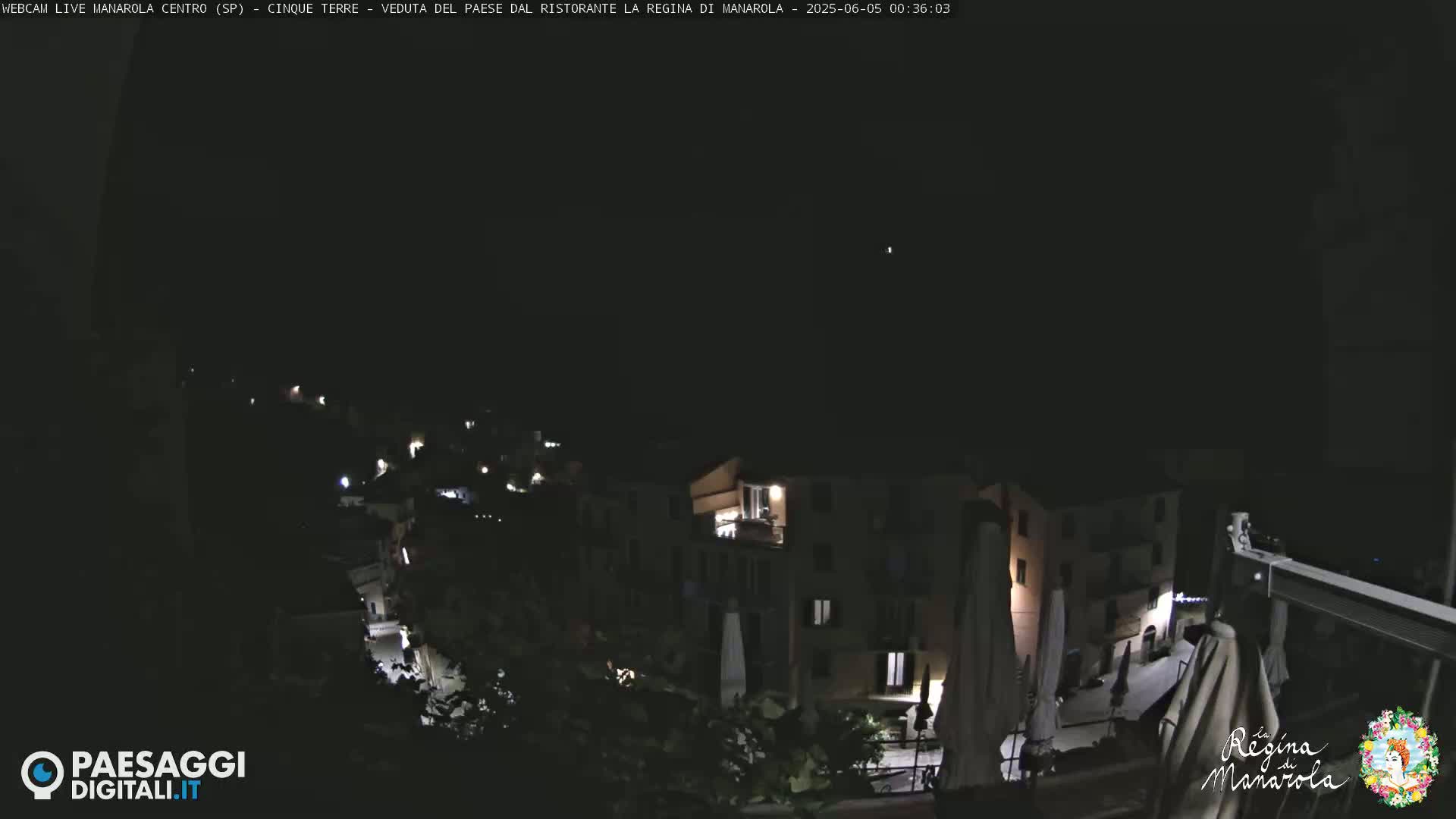 A nighttime, high-angle view of a small, illuminated town nestled on a hillside under a dark sky.