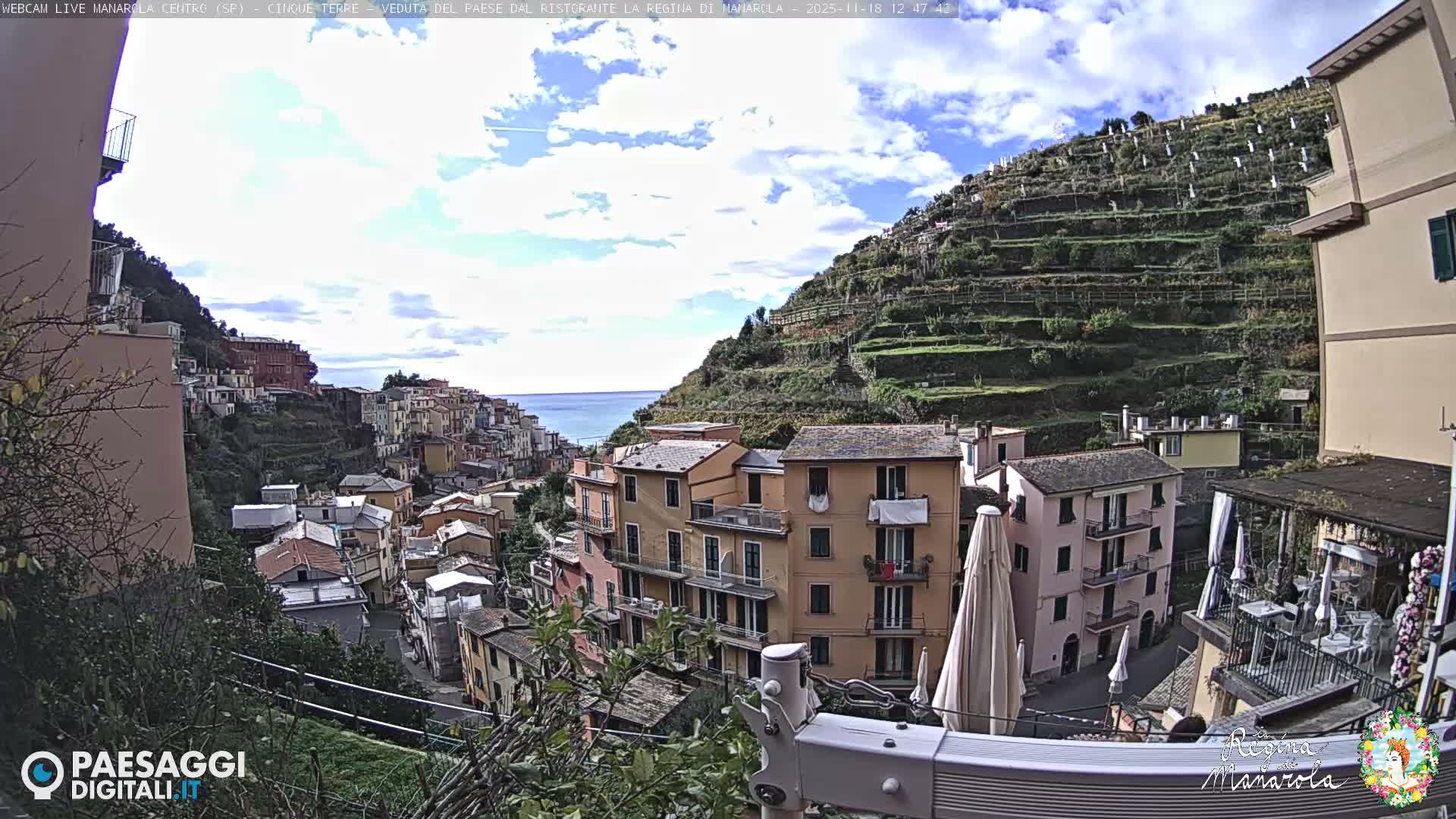 A clear, dark night sky with a single bright light overlooks a hillside town, where buildings and streets are softly illuminated by numerous artificial lights.