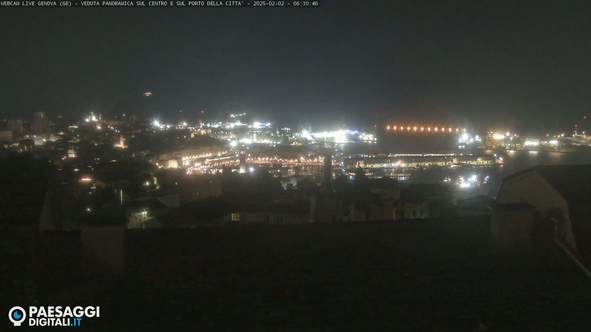 A nighttime, hazy view of a city's illuminated harbor and surrounding buildings.