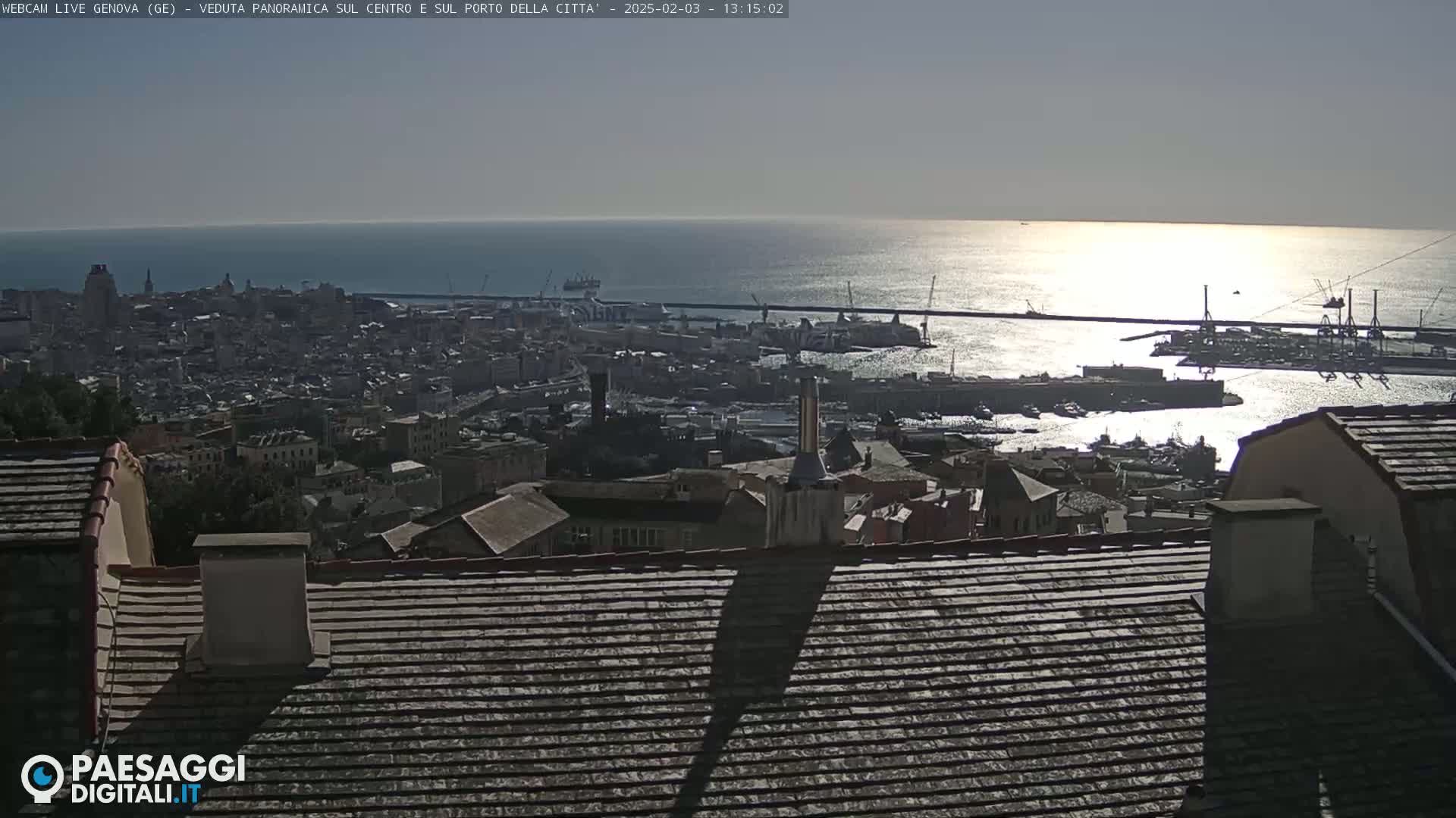 A panoramic view of a city and harbor on a sunny day, with a calm sea extending to the horizon.
