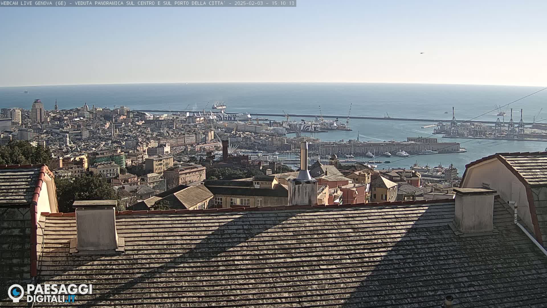 A panoramic view of a city and harbor on a clear, sunny day, with the cityscape extending to a calm ocean.