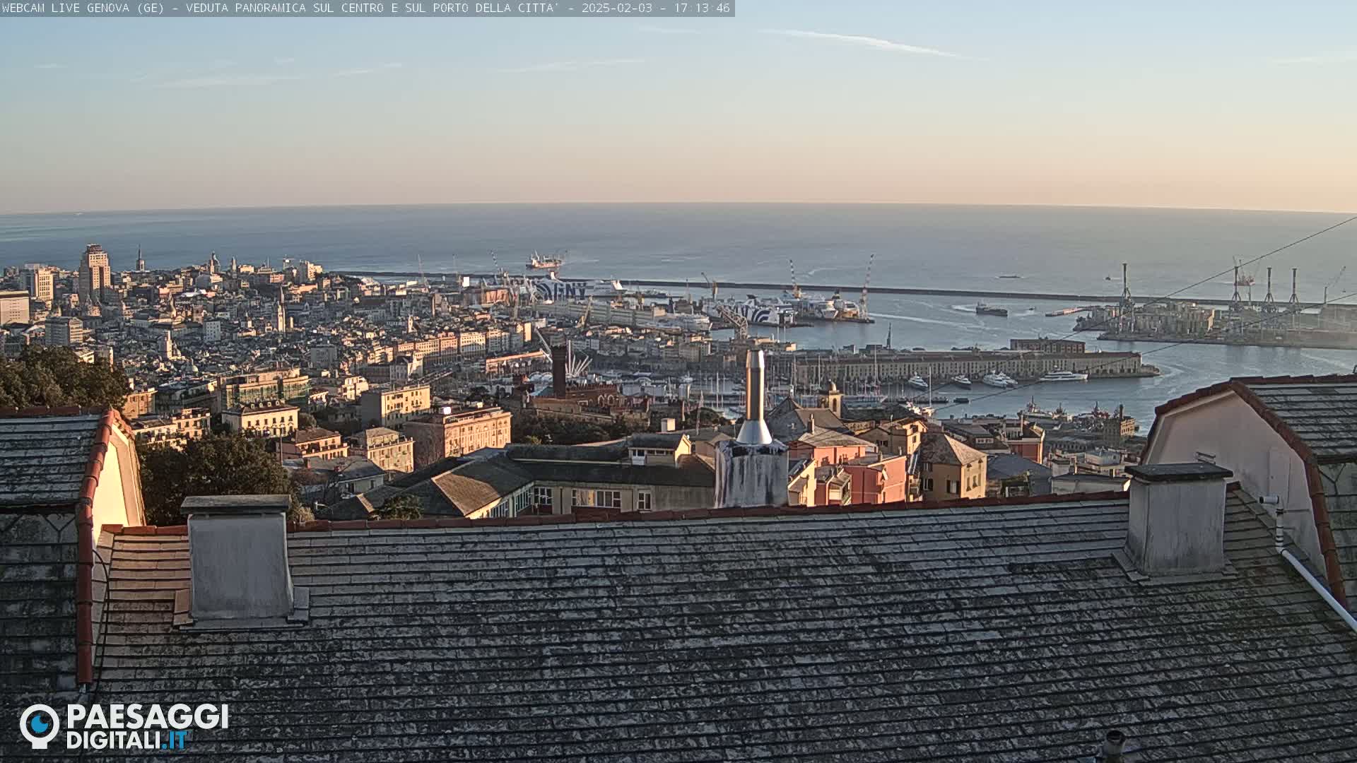 A panoramic view of a city and harbor at sunset, showing calm waters and many buildings.