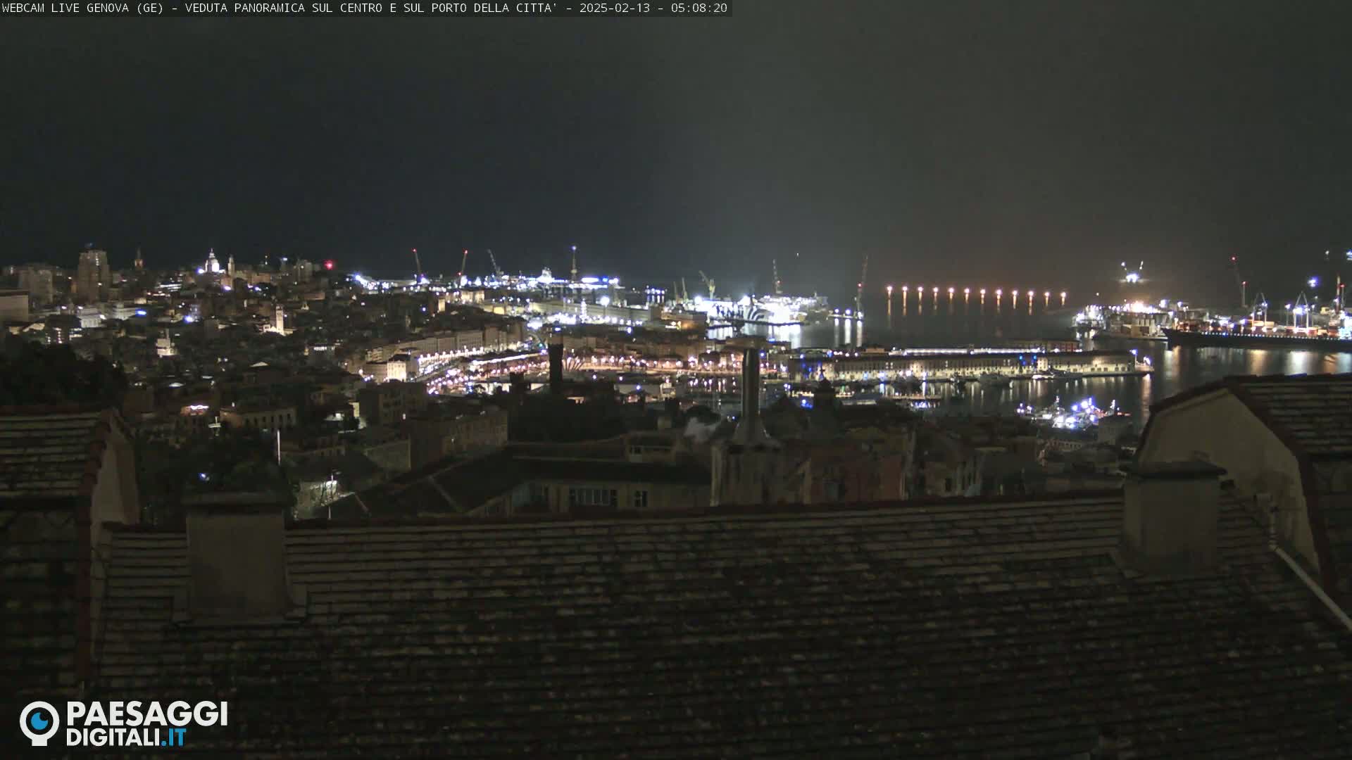 A nighttime panoramic view of a city's harbor and illuminated cityscape.