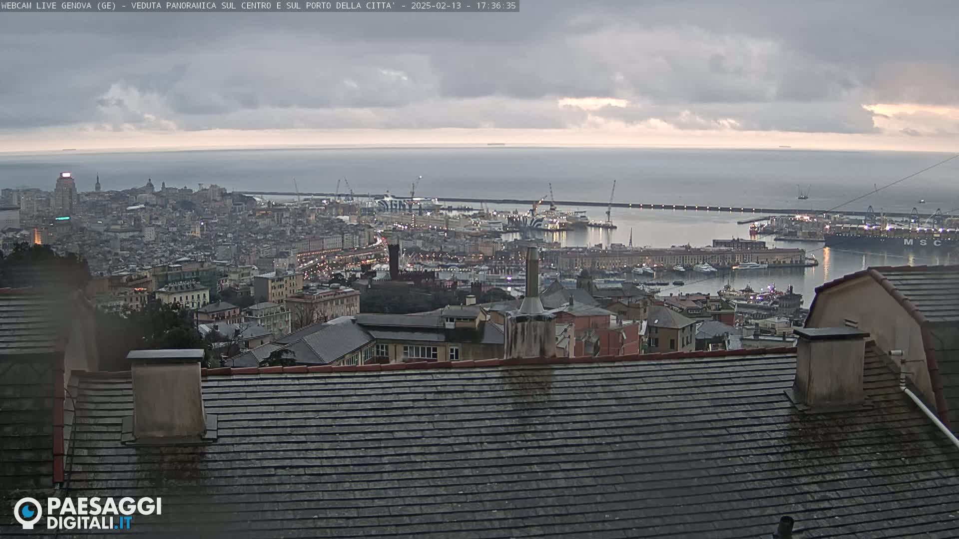 A panoramic view of a city harbor with many buildings and ships under a cloudy sky.