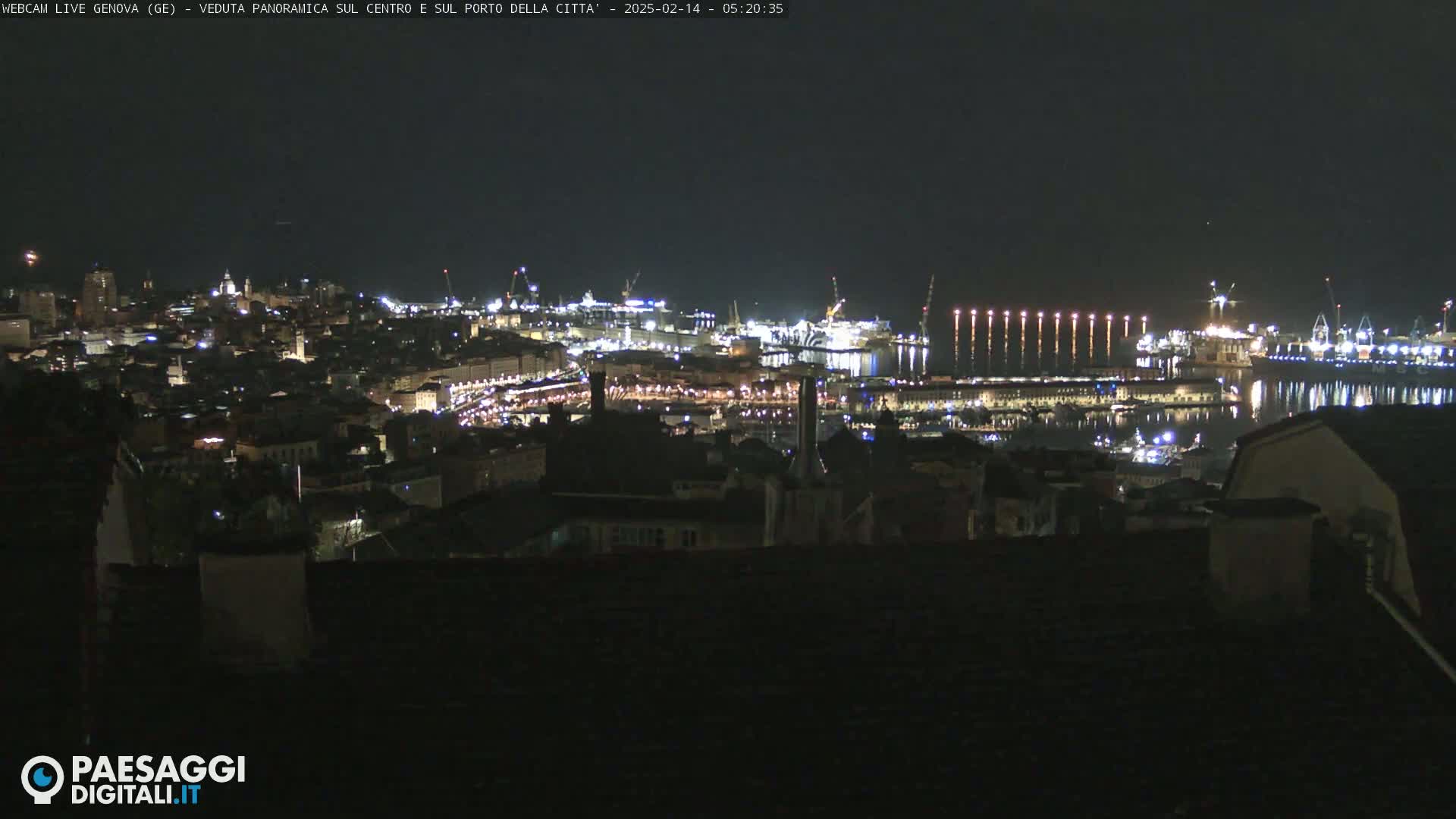 A nighttime panoramic view of a city's harbor and illuminated buildings.