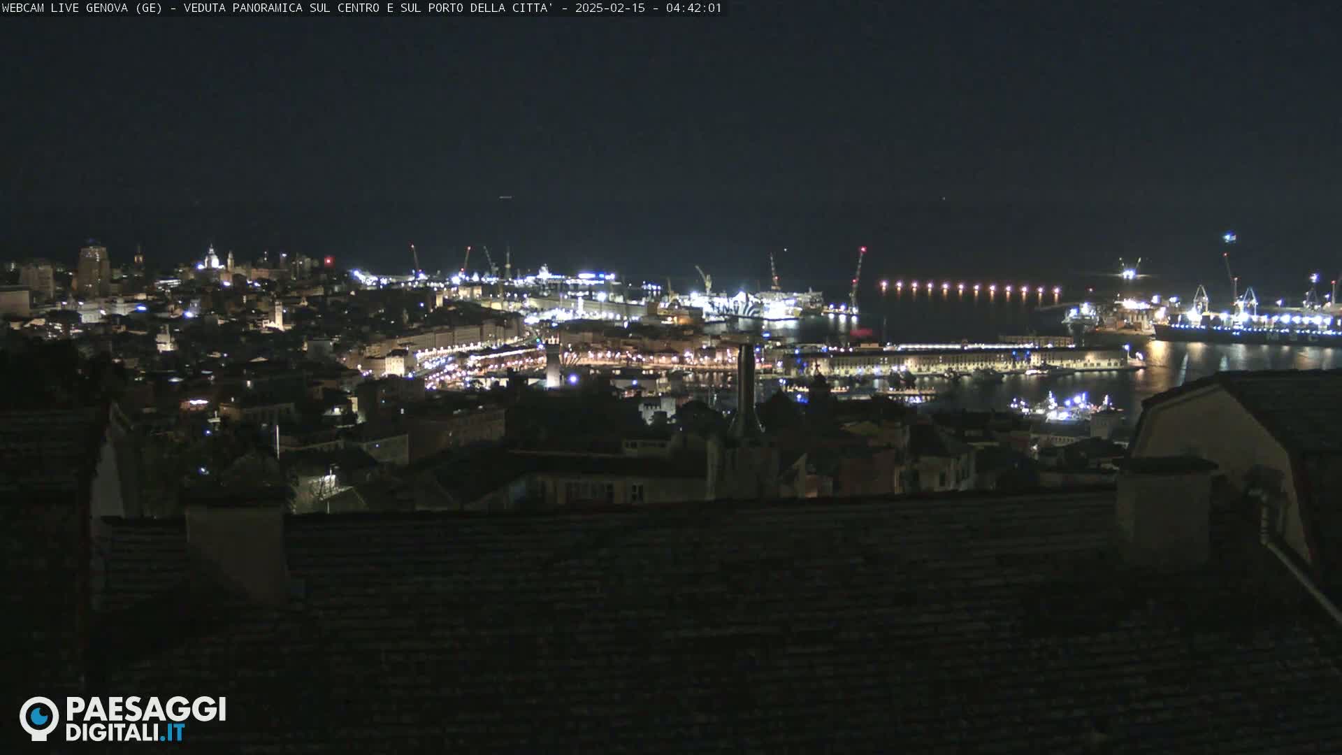 A nighttime panoramic view of a city's illuminated harbor and buildings, under a clear, dark sky.