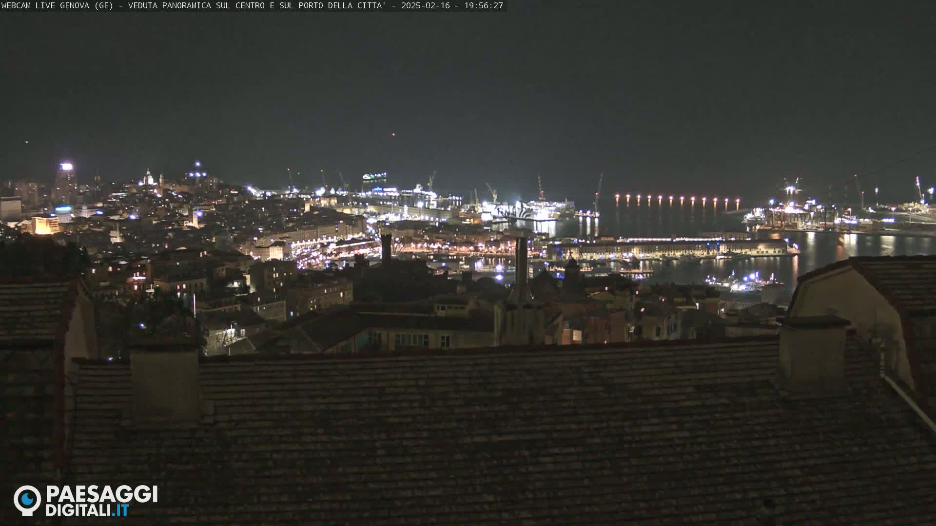 A nighttime panoramic view of a city's illuminated harbor and buildings under a clear, dark sky.