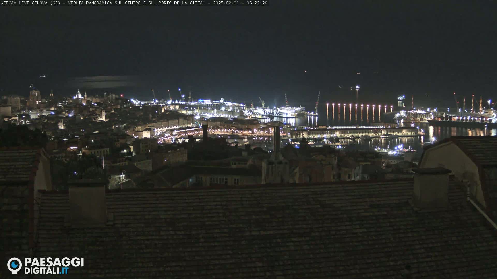 A nighttime panoramic view of a city's harbor and cityscape, brightly lit against a dark sky.