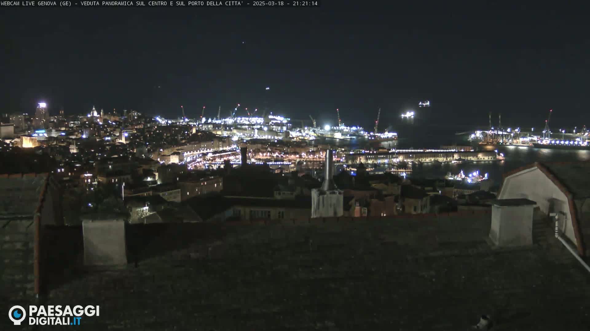 A nighttime panoramic view of a city's harbor and illuminated buildings, under a clear, dark sky.