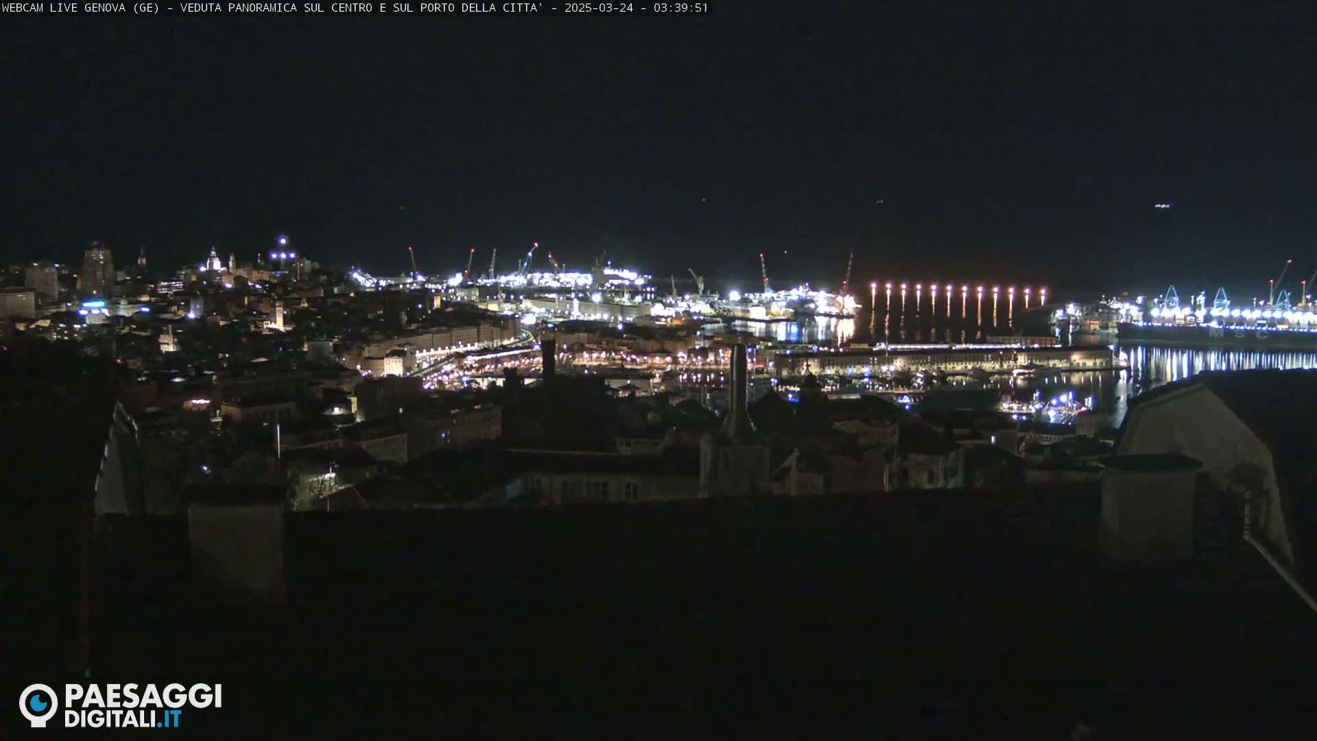 A nighttime, panoramic view of a city's illuminated harbor and cityscape.