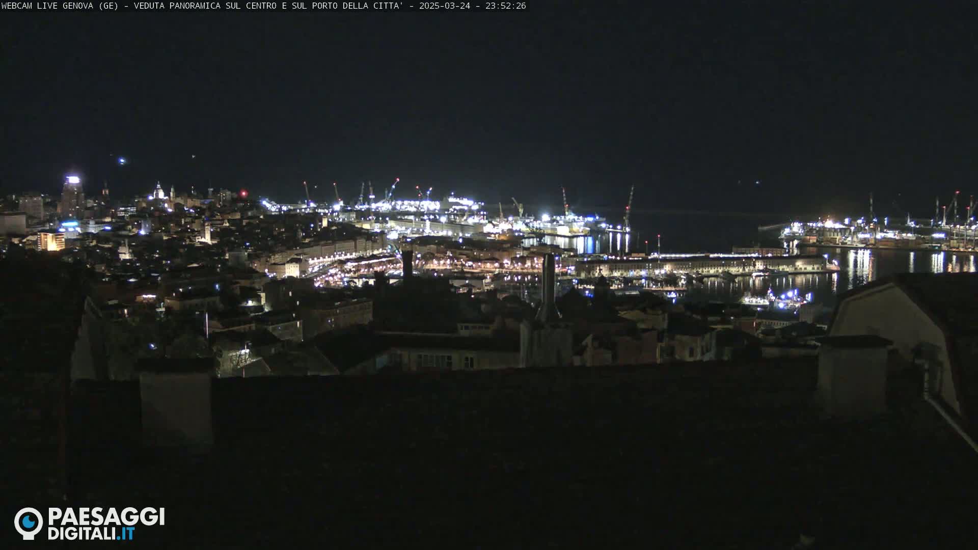 A nighttime panoramic view of a city's illuminated harbor and buildings.