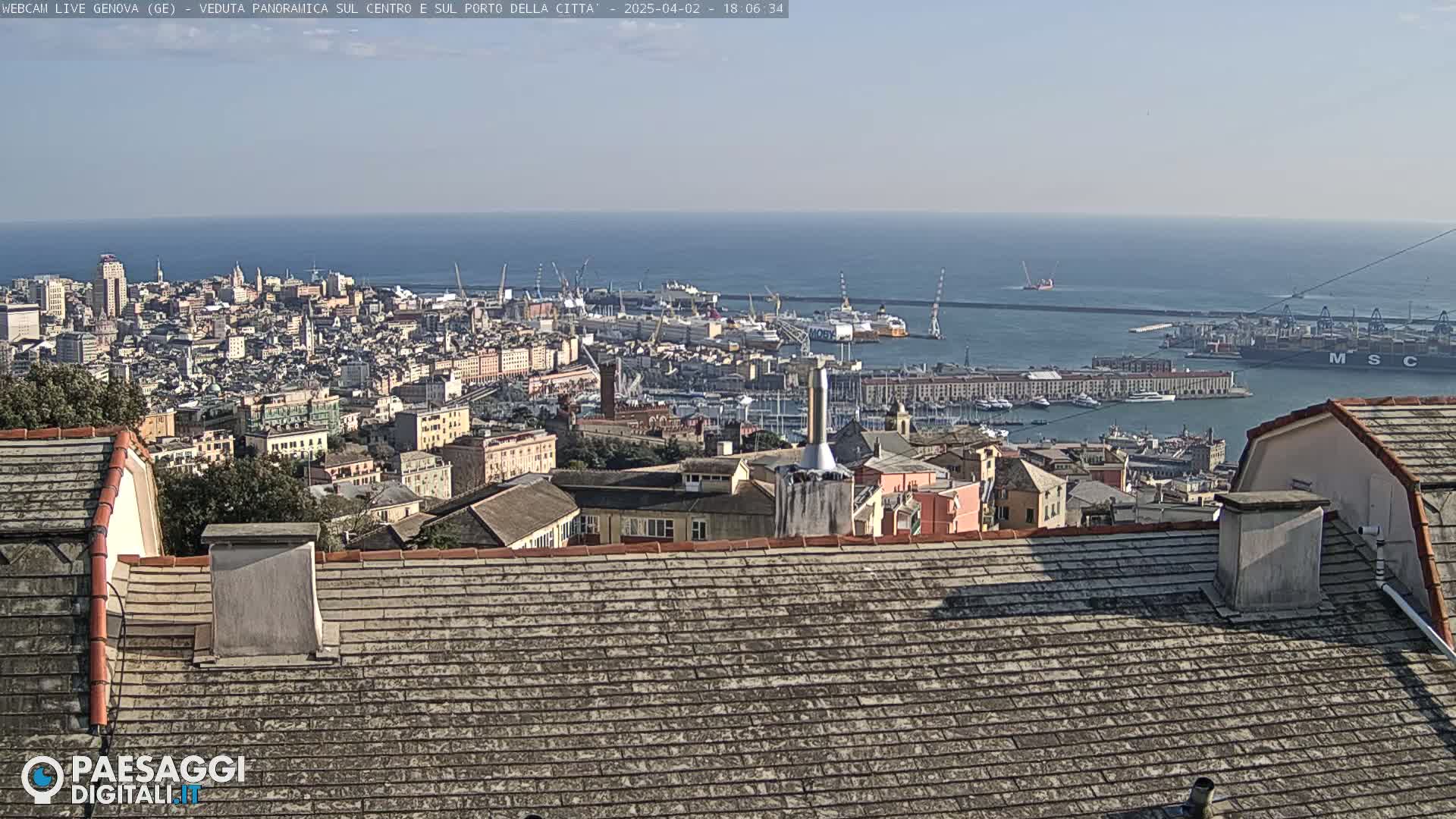 A panoramic view of a city and harbor on a clear day, with a large body of water extending to the horizon.