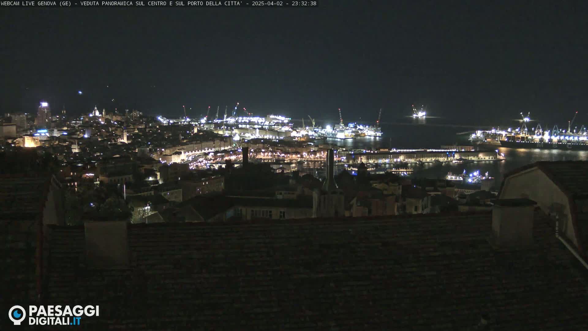 A nighttime, panoramic view of a city's illuminated harbor and buildings.