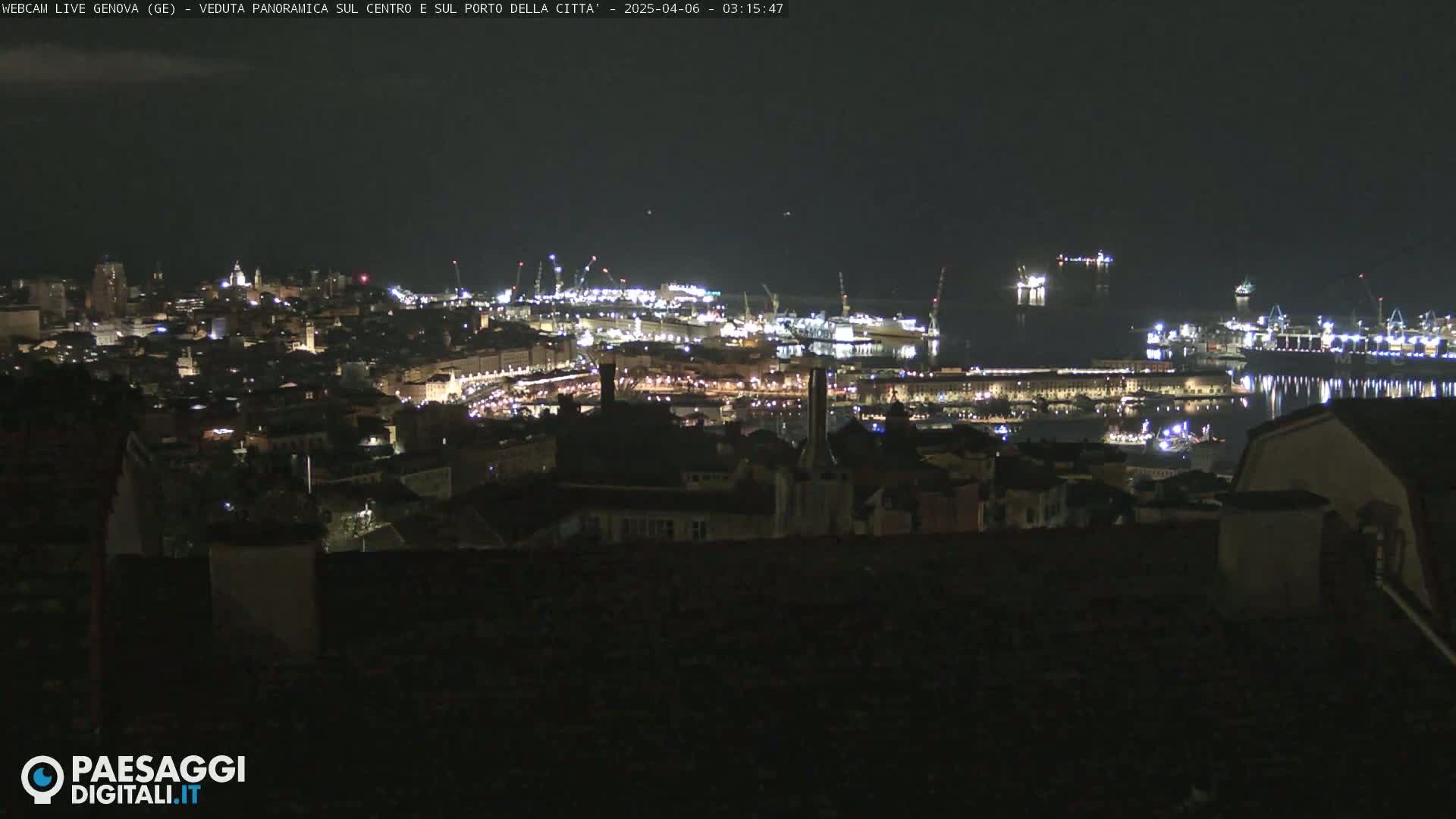 A nighttime, panoramic view of a city's illuminated harbor and buildings.