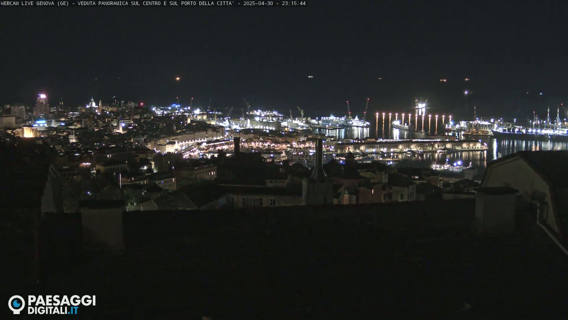 A nighttime panoramic view of a city's harbor and illuminated cityscape.
