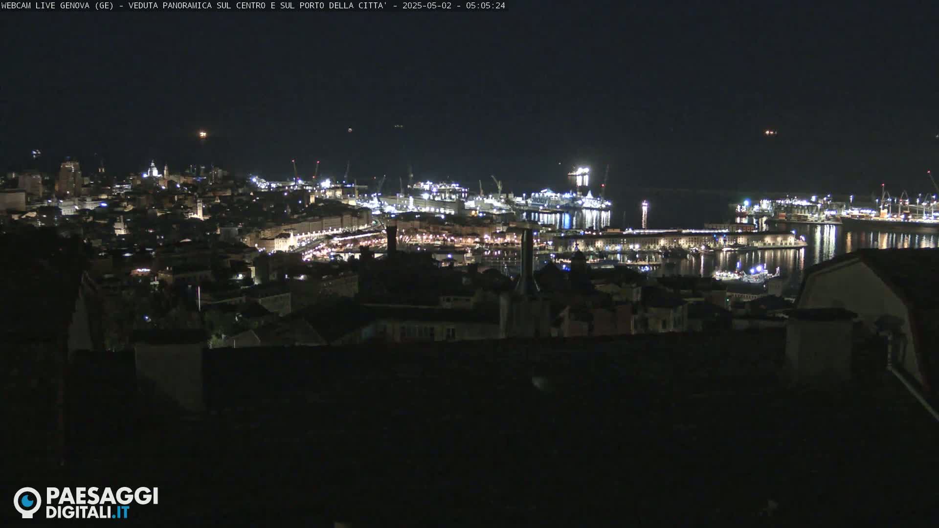 A nighttime, panoramic view of a city's harbor and illuminated cityscape.