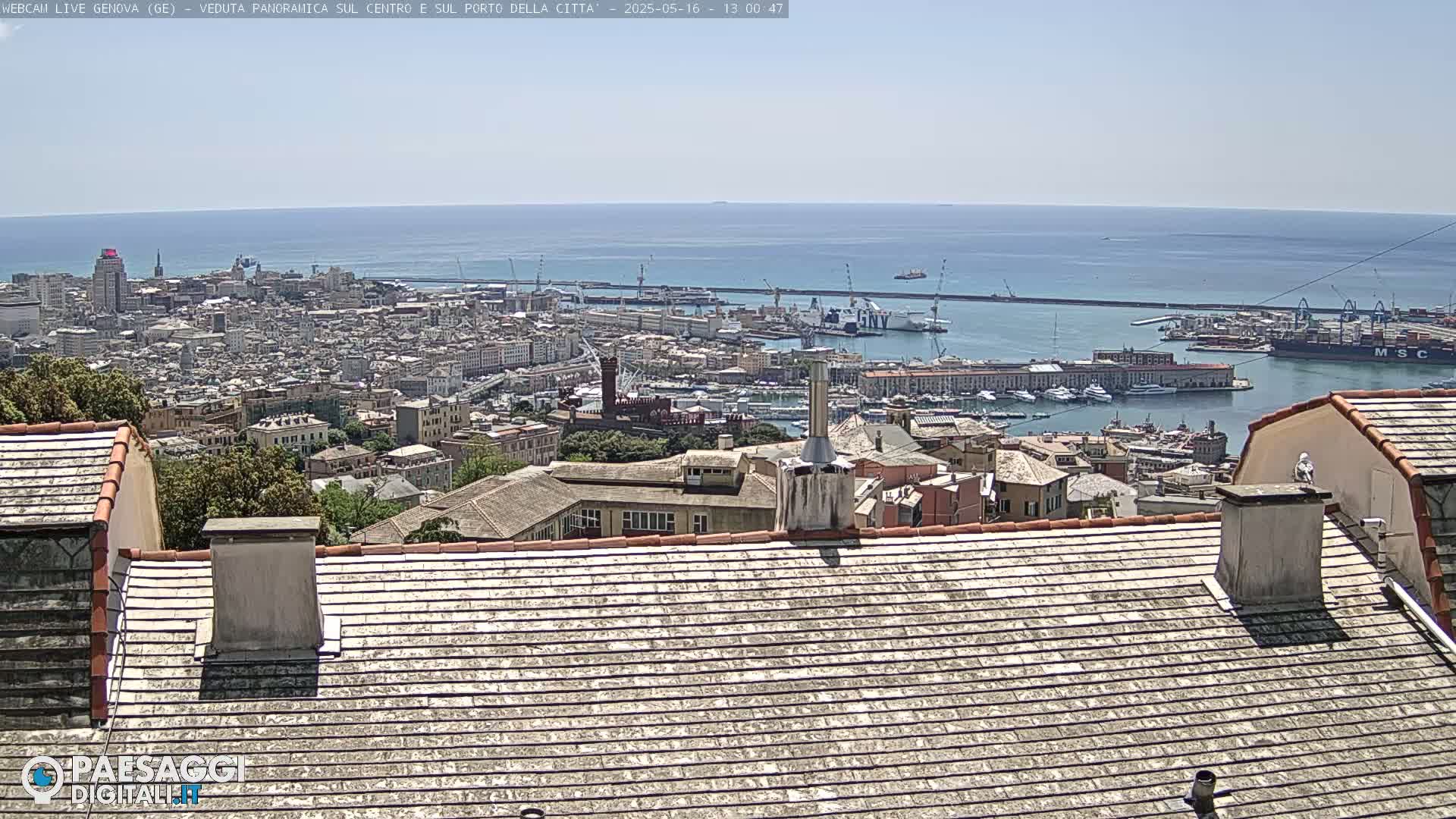 A panoramic view on a sunny day shows a city harbor filled with ships and boats, extending to a wide expanse of blue ocean.