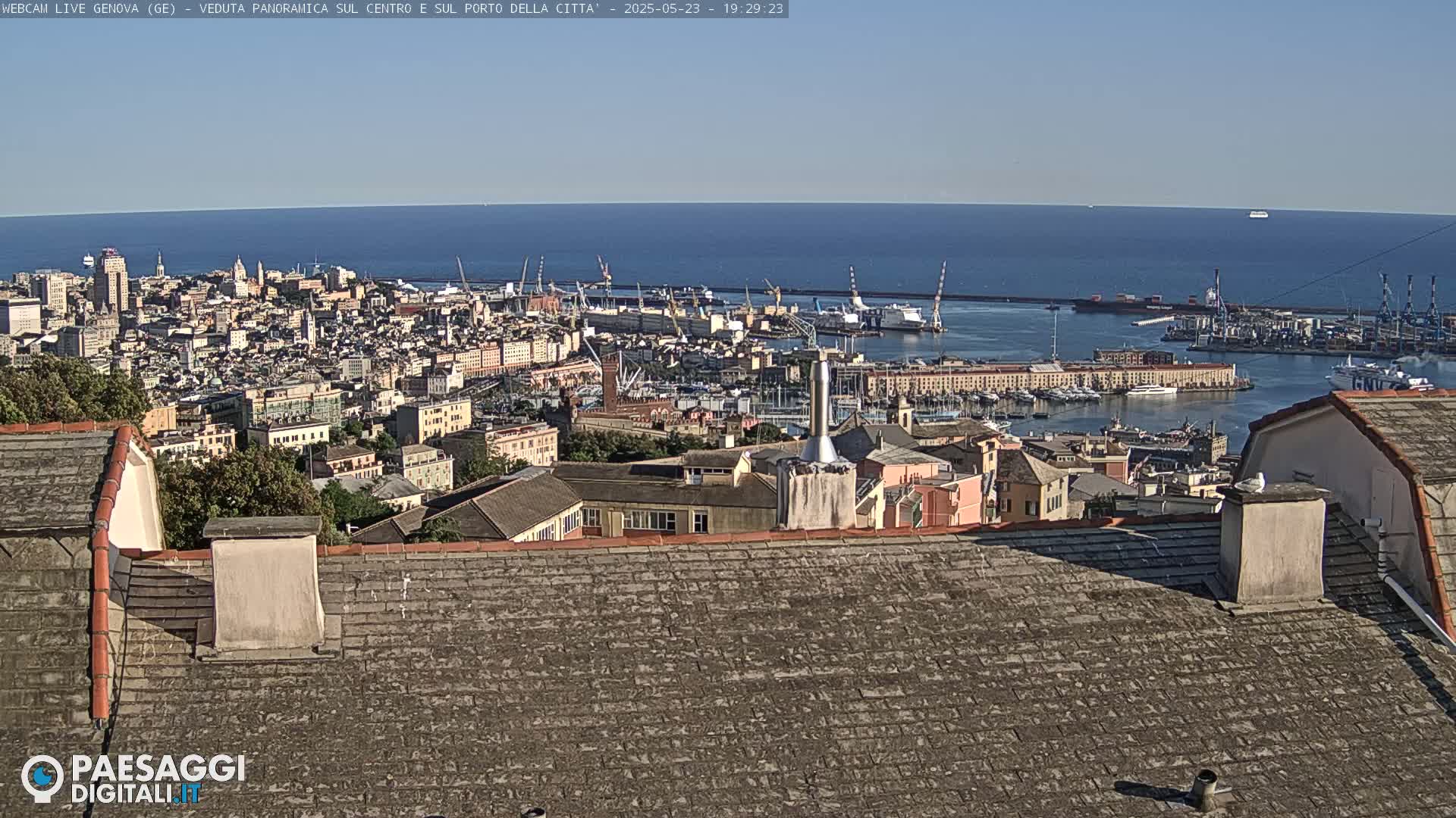 A sprawling city with a large port and a clear blue sea stretches to the horizon under a sunny sky.