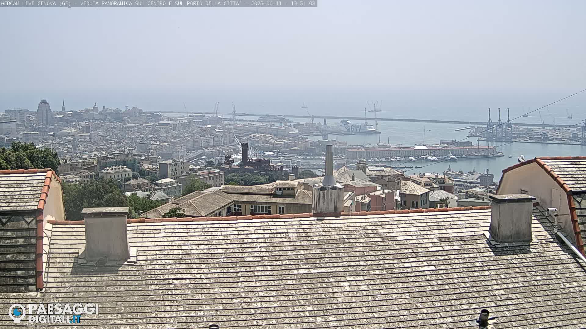 A hazy, sunny day overlooks a sprawling city and its busy port from a rooftop vantage point.