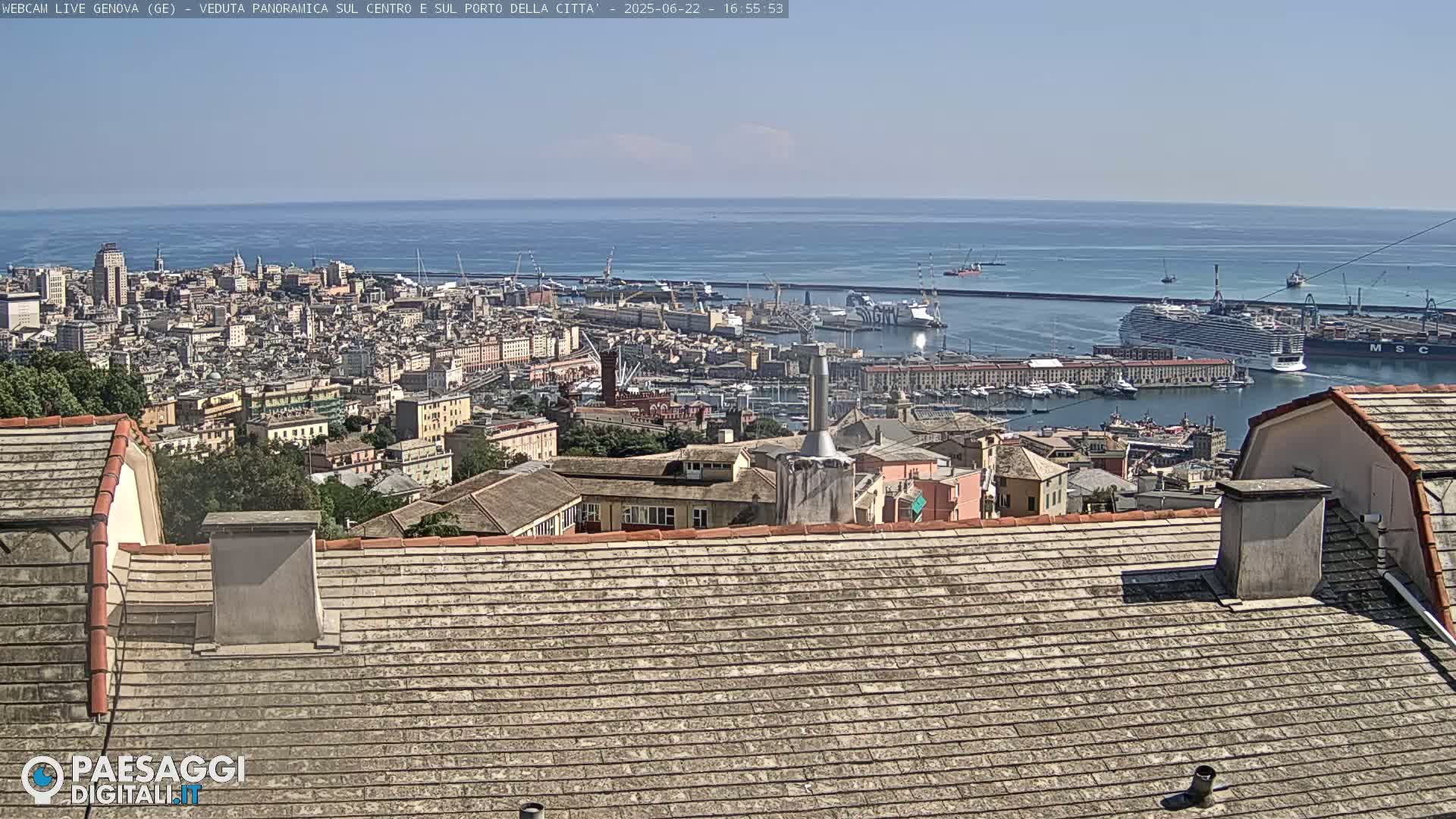 A panoramic view of a city harbor and cityscape on a sunny day, seen from a rooftop.