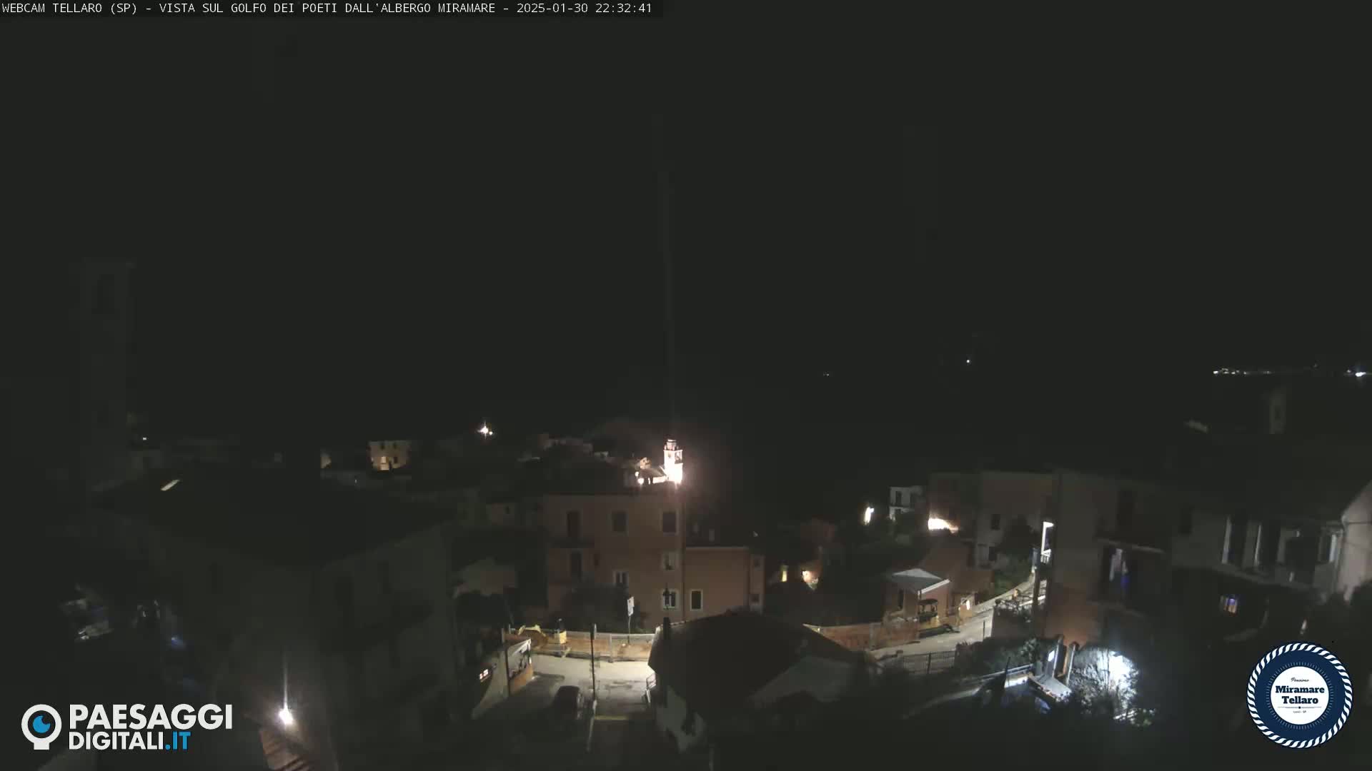 A nighttime view of a small town illuminated by scattered lights under a clear, dark sky.