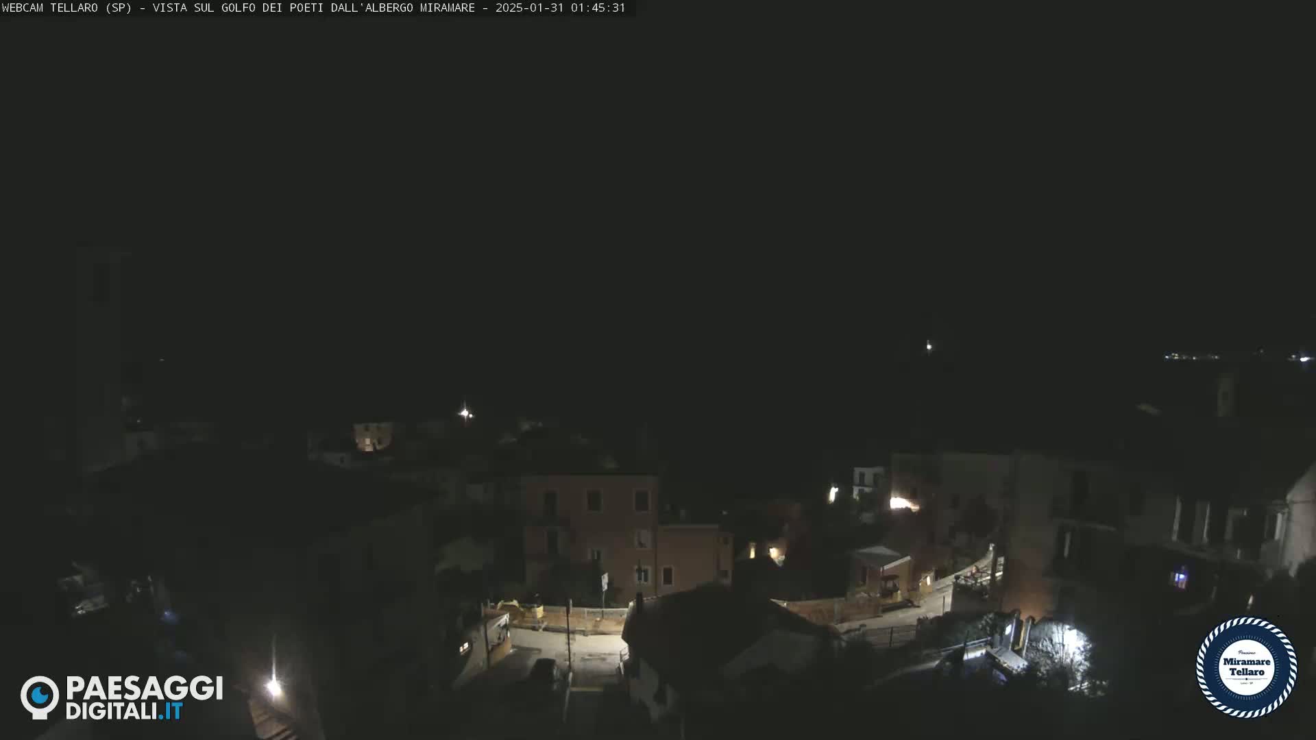 A nighttime, dark view of a small town nestled on a hillside.