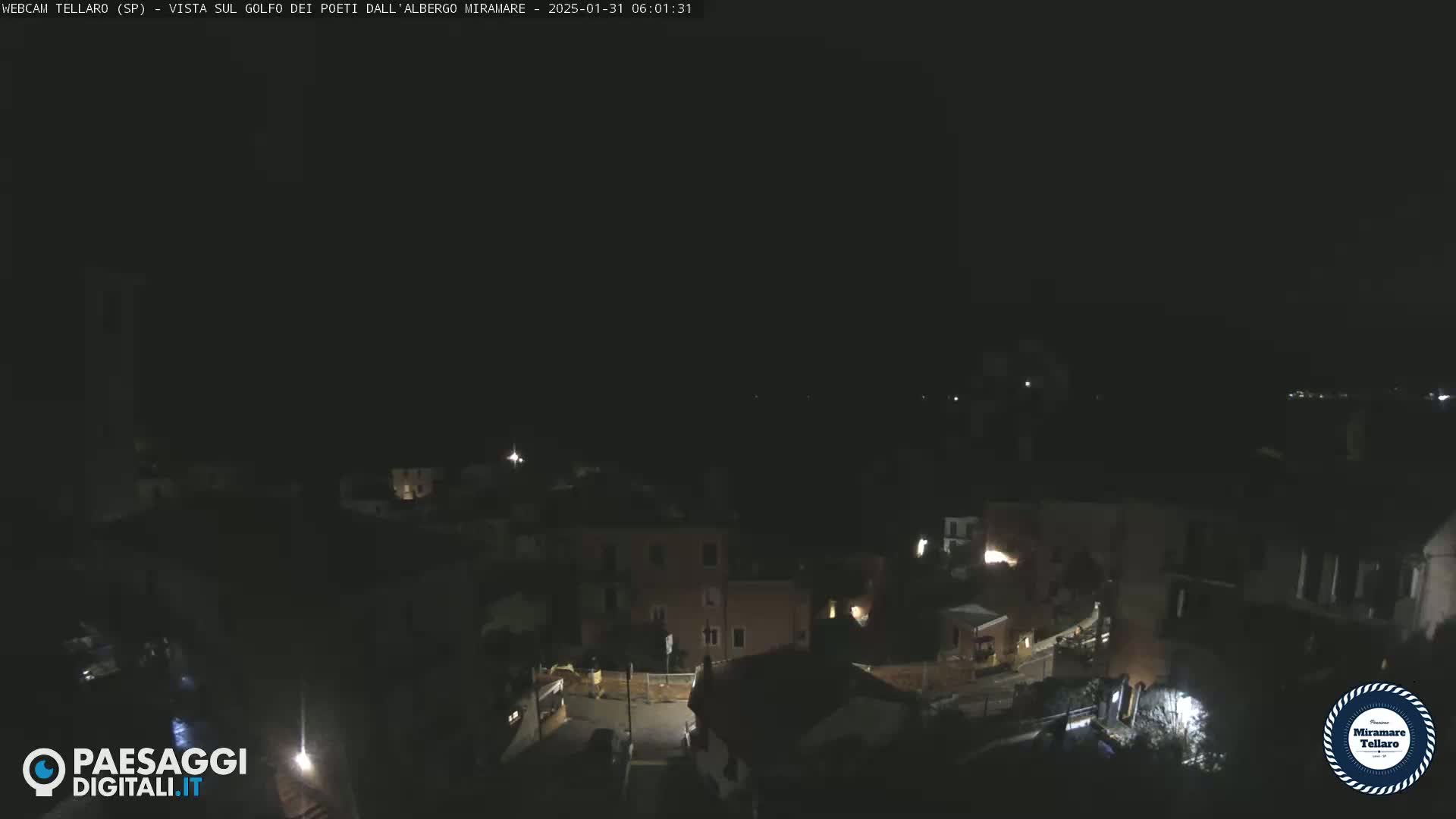 A nighttime, high-angle view of a dimly lit town, with a few scattered lights visible.
