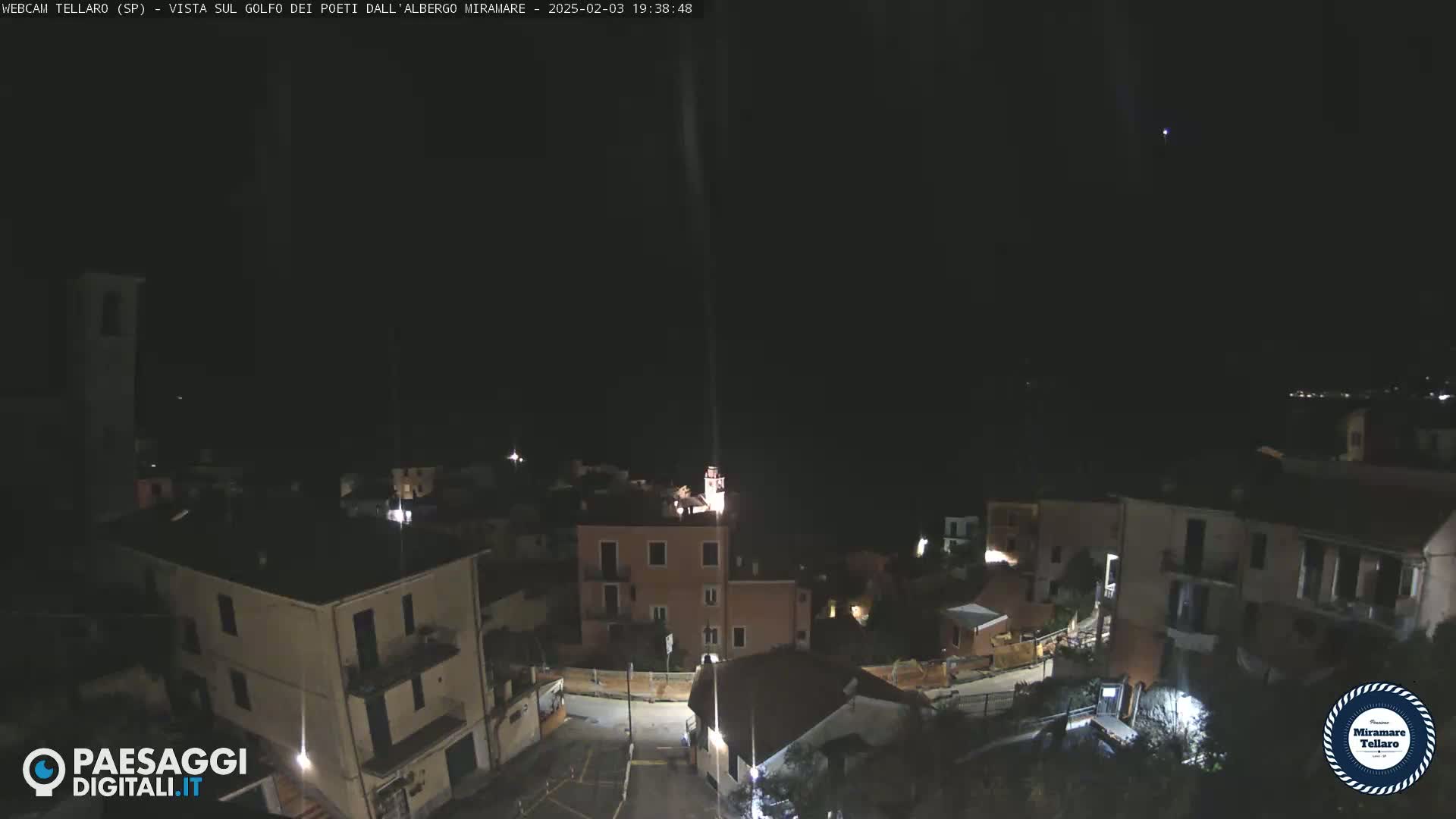 A nighttime, aerial view of a small town nestled on a hillside under a clear, dark sky.