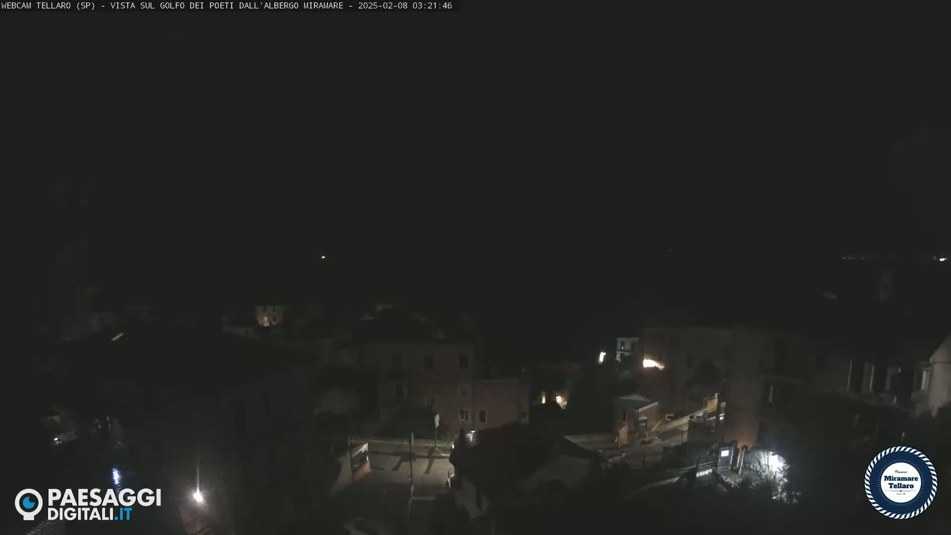 A nighttime, high-angle view of a dimly lit town, possibly near the coast.
