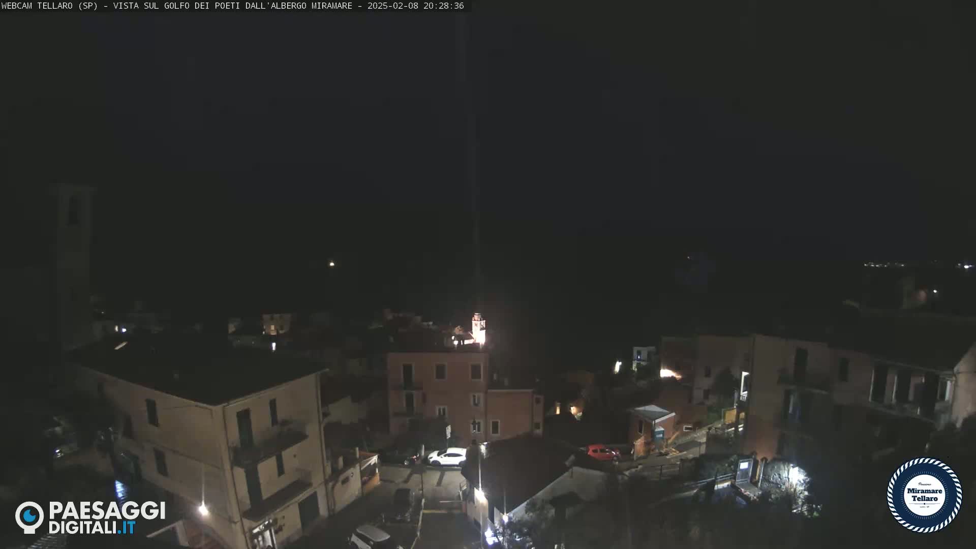 A nighttime, high-angle view of a small town nestled against a dark hillside.