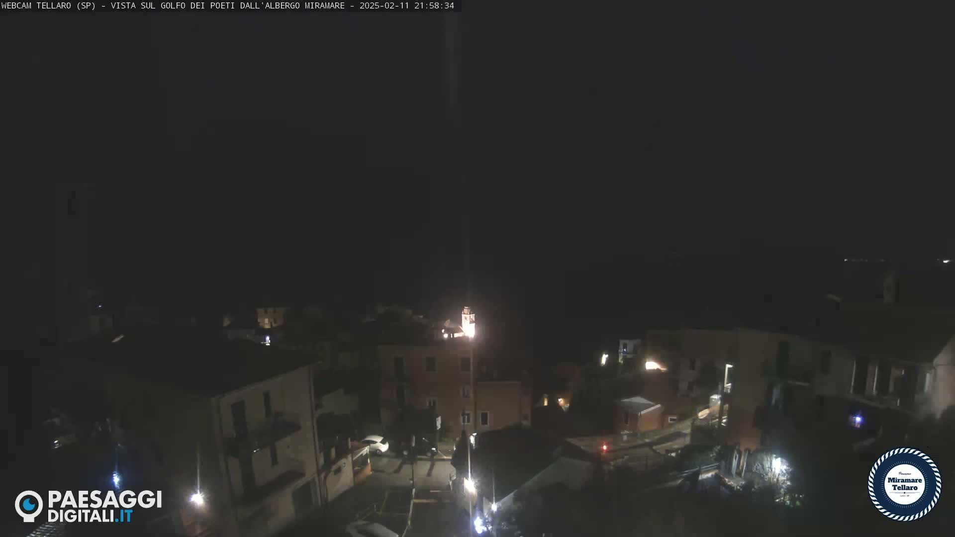 A nighttime, aerial view of a dimly lit town with a few lights visible.