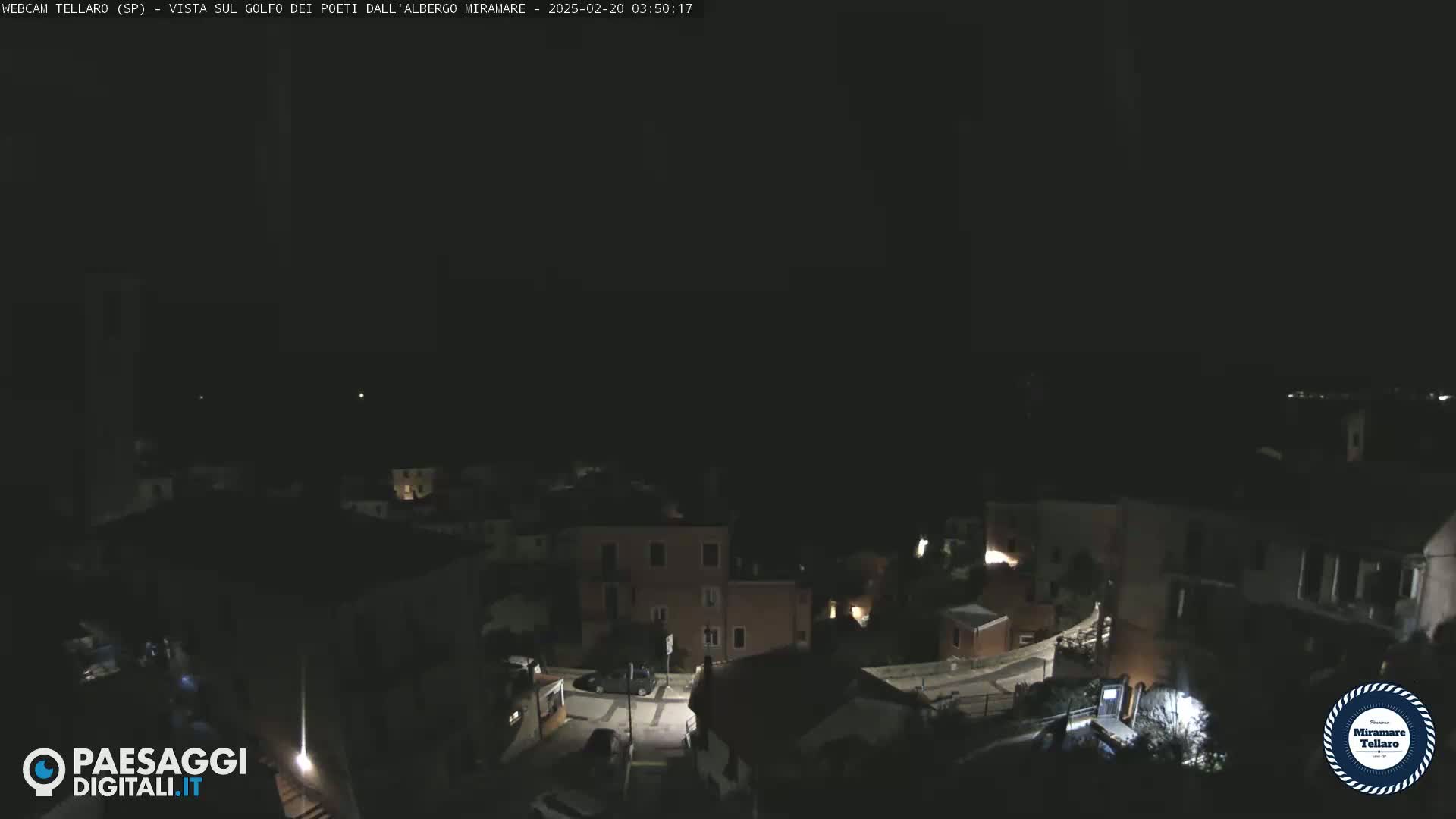 A nighttime, overhead view of a small town with dimly lit buildings and streets.