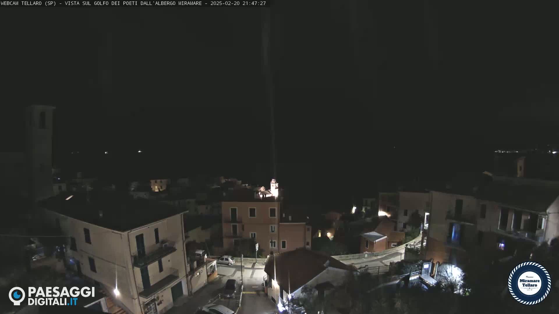 A nighttime, high-angle view of a small town nestled on a hill, illuminated by scattered lights.