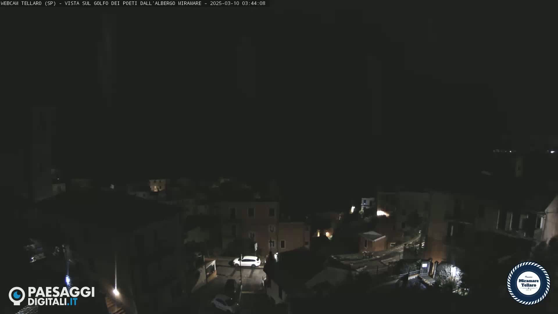 A nighttime, high-angle view of a dimly lit town with a few cars visible on the streets.