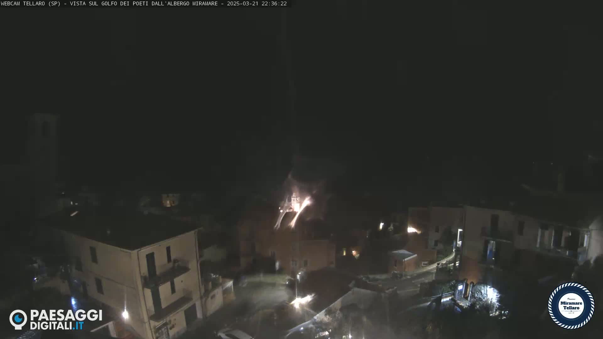 Fireworks explode over a dark, nighttime village.