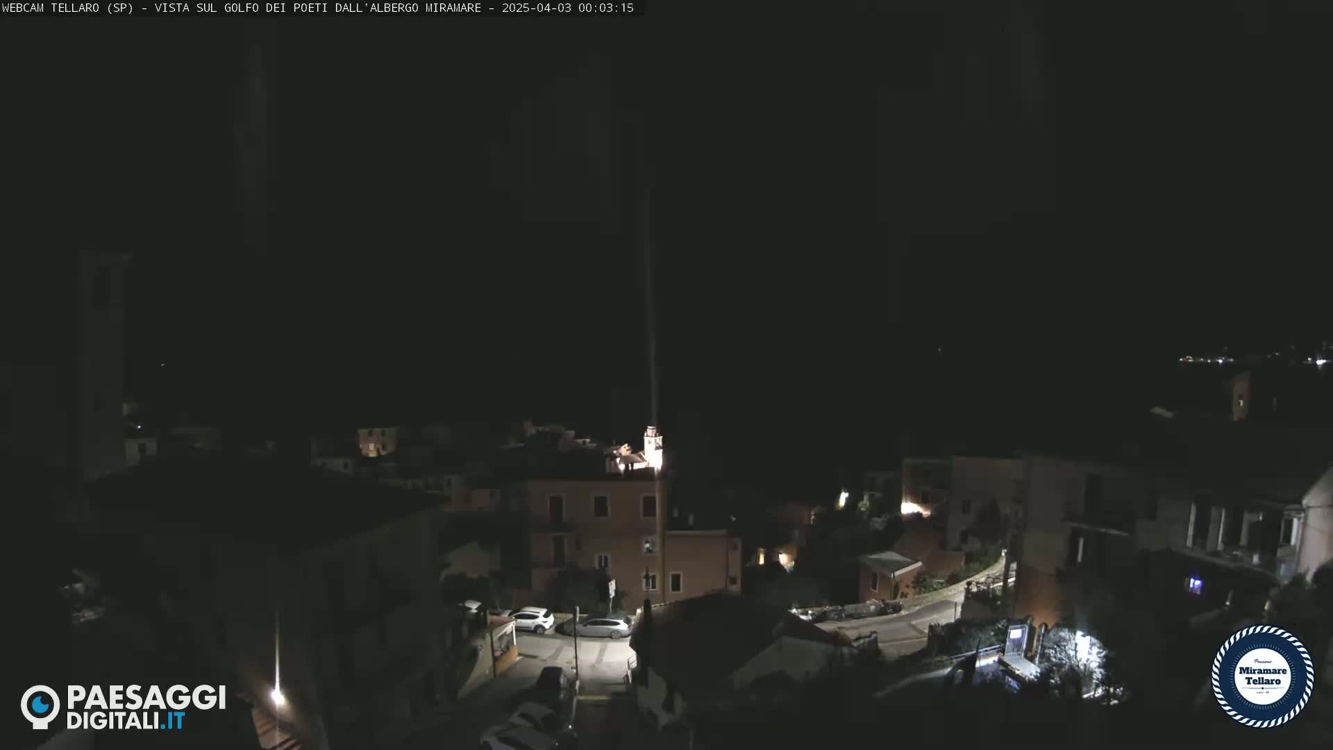 A nighttime, high-angle view of a small, dimly lit town nestled on a hillside.