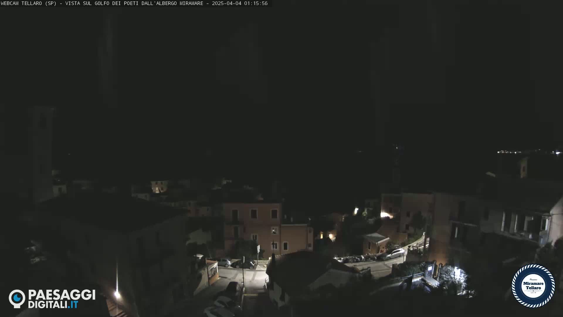 A nighttime, overhead view of a small town with dimly lit buildings and streets.