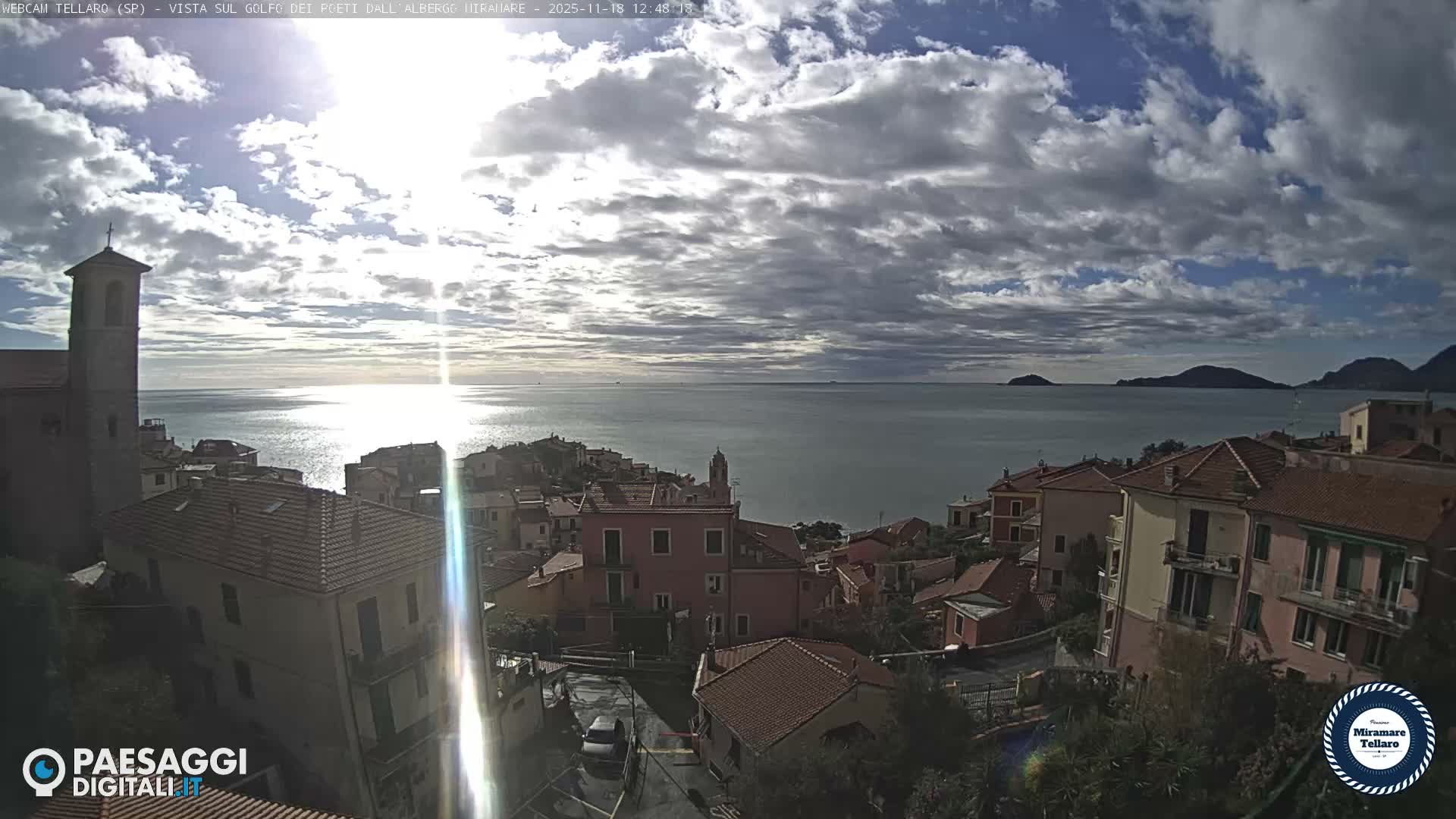 The image shows a nighttime view of a town with illuminated buildings and streetlights, overlooking a body of water with distant lights, under a clear sky.