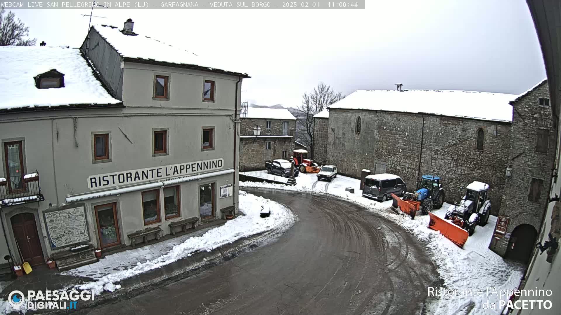 A snow-covered village square with several cars and snowplows, featuring a restaurant called "Ristorante L'Appennino."
