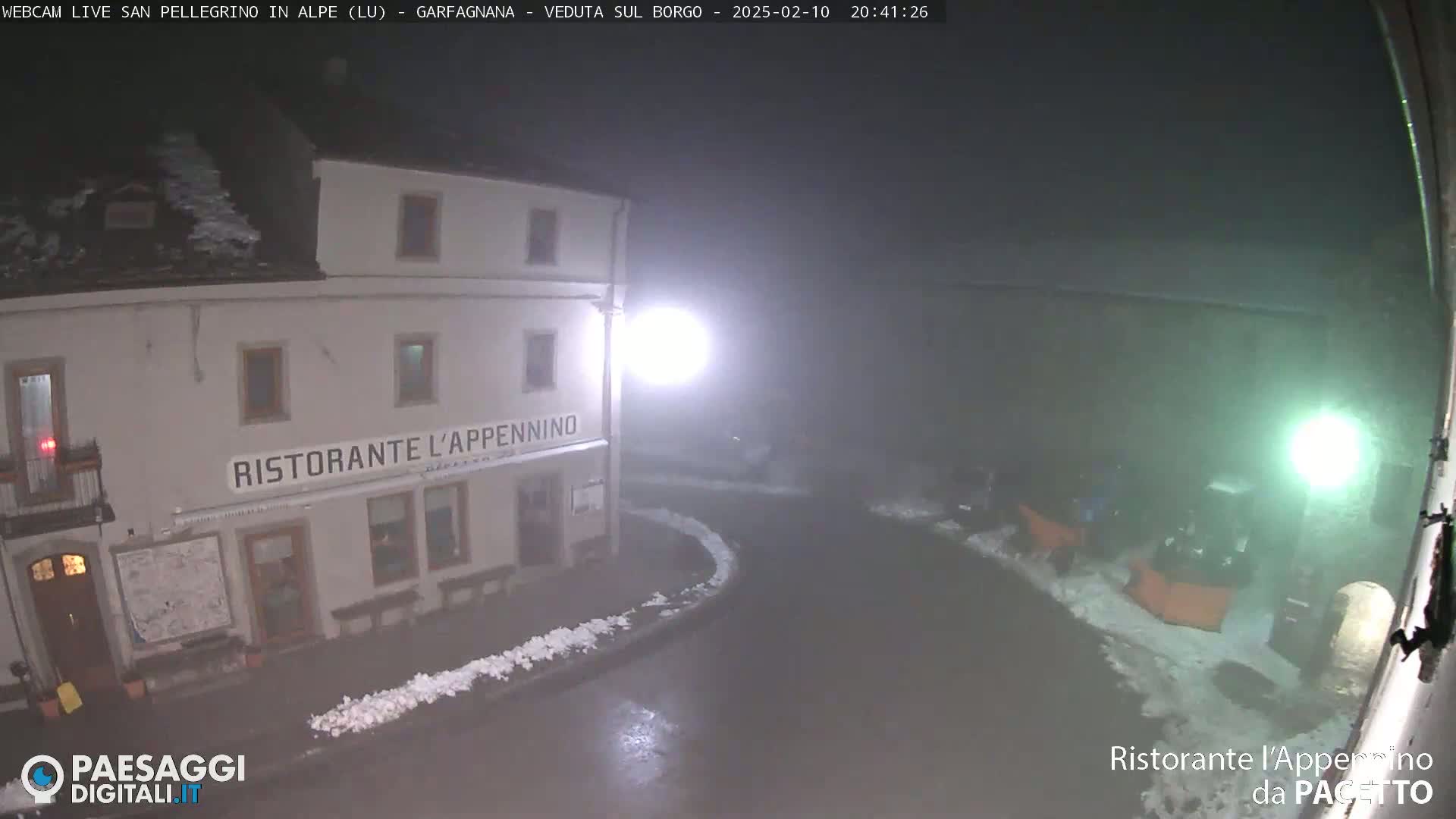 A nighttime view of a restaurant, "Ristorante l'Appennino," partially covered in snow, with a foggy or snowy atmosphere.