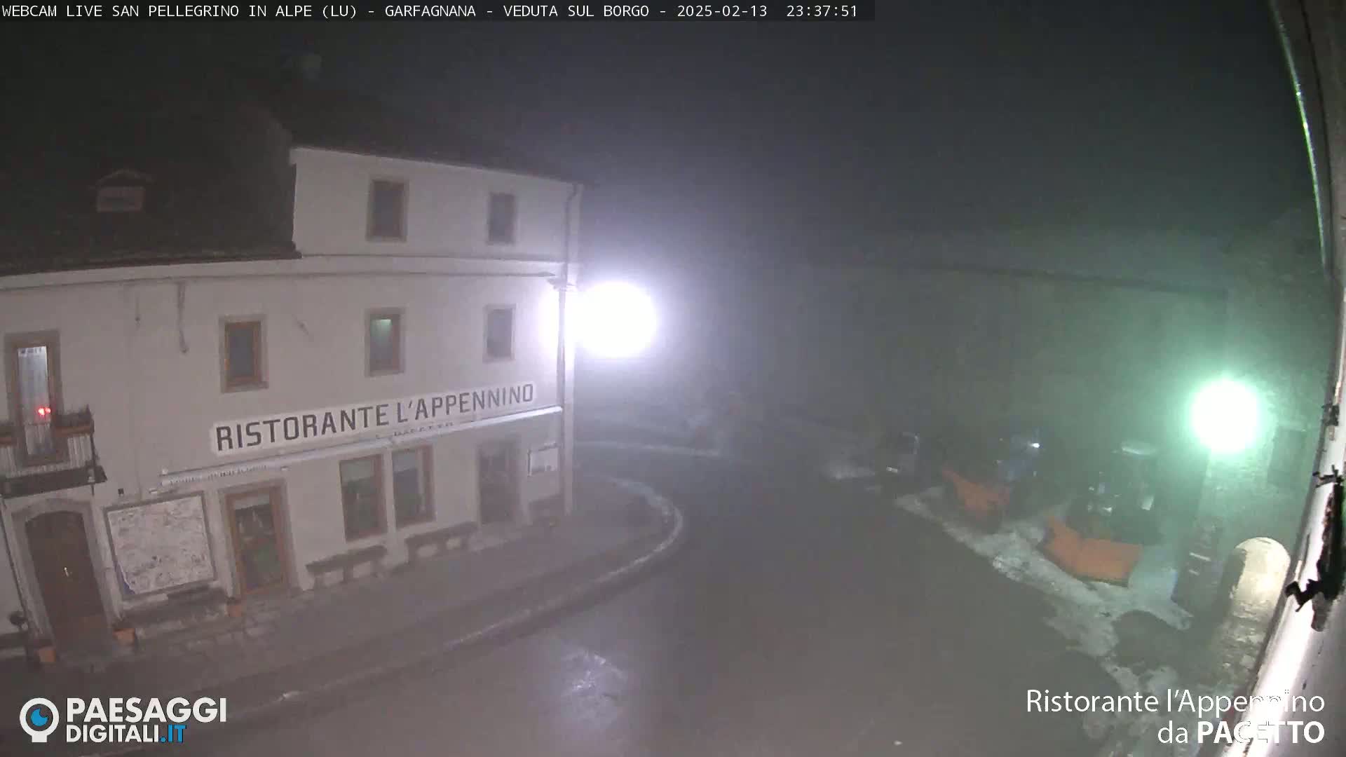 A nighttime, foggy view of a restaurant called "Ristorante l'Appennino," situated on a mostly empty street with some snow visible on the ground.