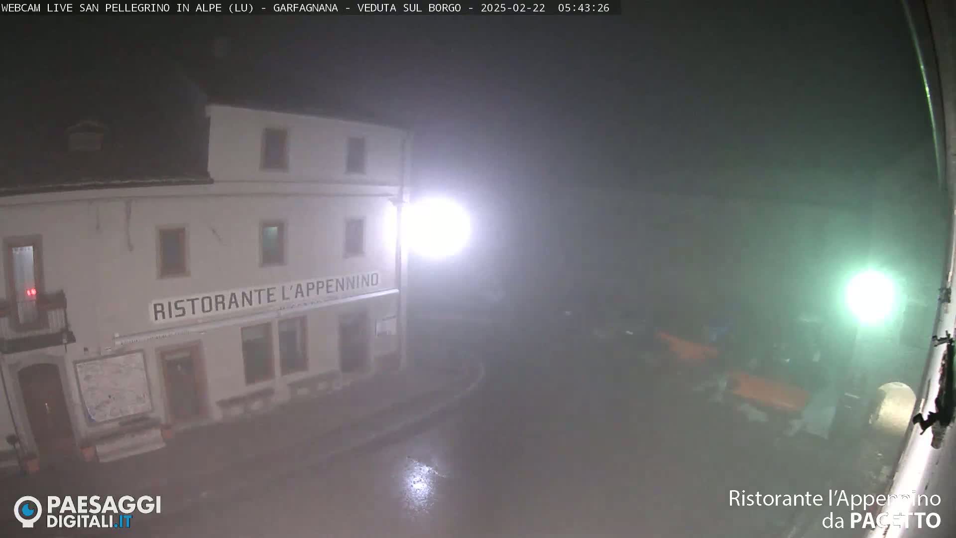 A fog-shrouded, nighttime view of a restaurant building illuminated by bright lights.