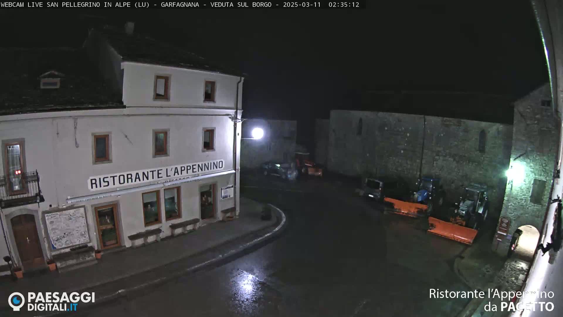 A nighttime, wet street scene shows a restaurant called Ristorante l'Appennino, several parked cars, and snow removal equipment.