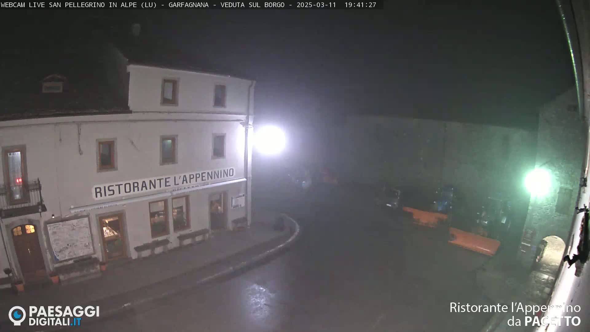 A nighttime view of a restaurant named "Ristorante l'Appennino" on a wet street, under hazy, dimly lit conditions.