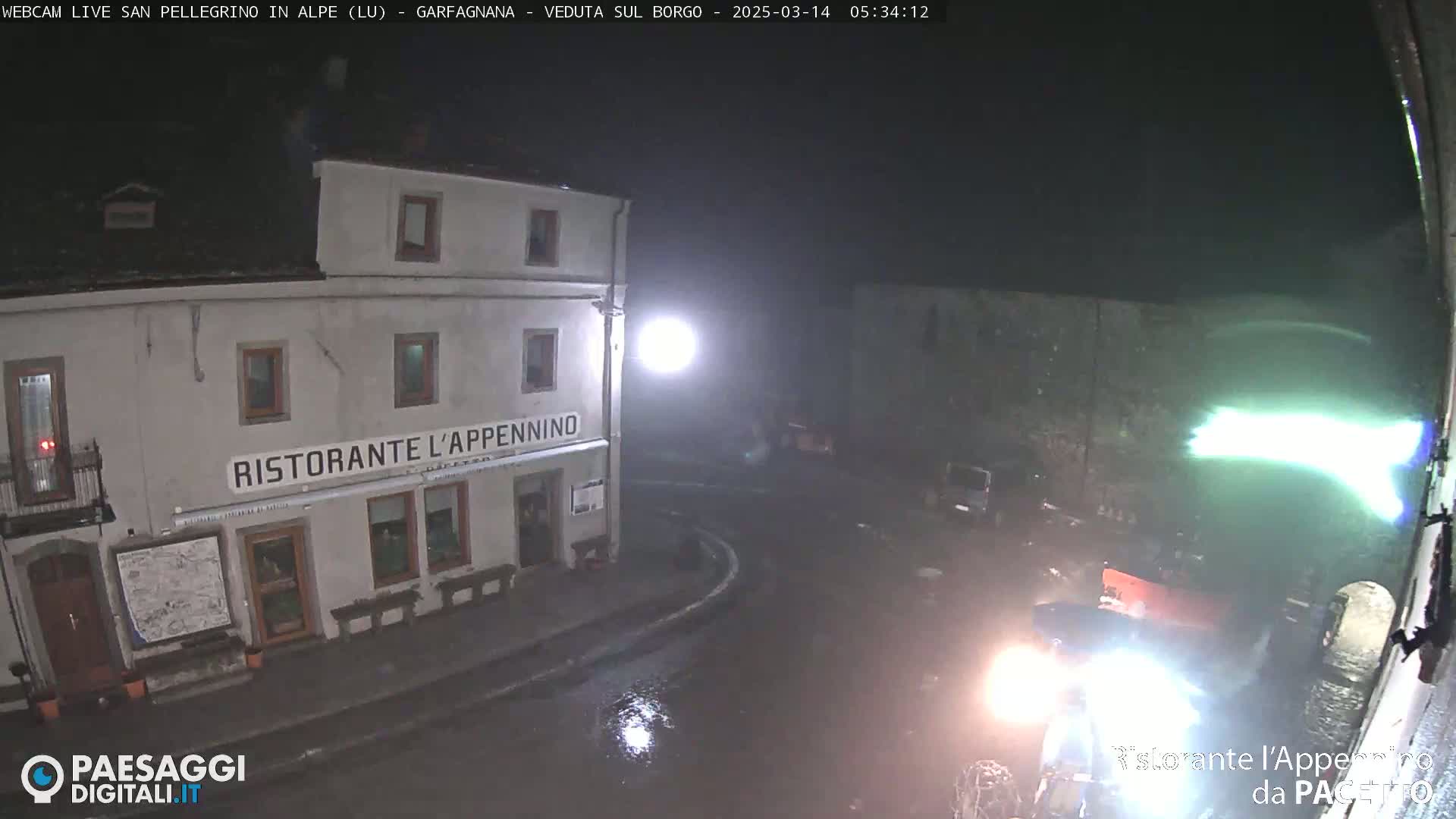 A nighttime, rainy view of a restaurant called "Ristorante L'Appennino" situated on a street corner, with a vehicle partially visible in the foreground.