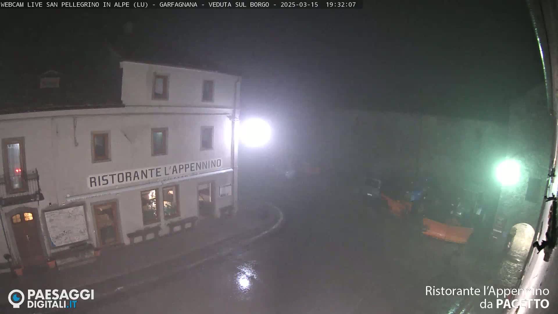 A restaurant at night in rainy conditions is illuminated by streetlights.