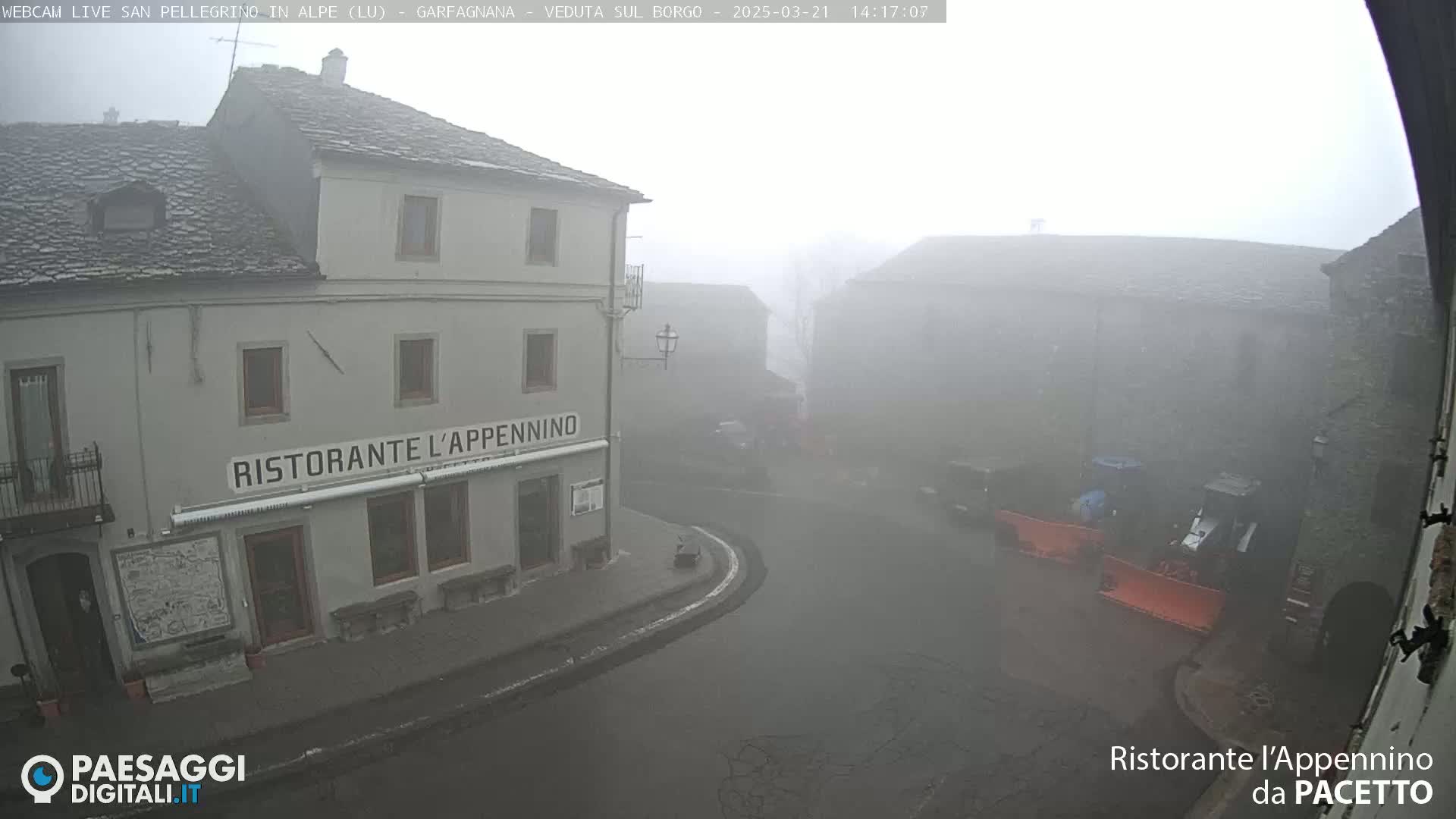 A foggy town square is visible, with stone buildings and a restaurant in the foreground, and snowplows in the background.