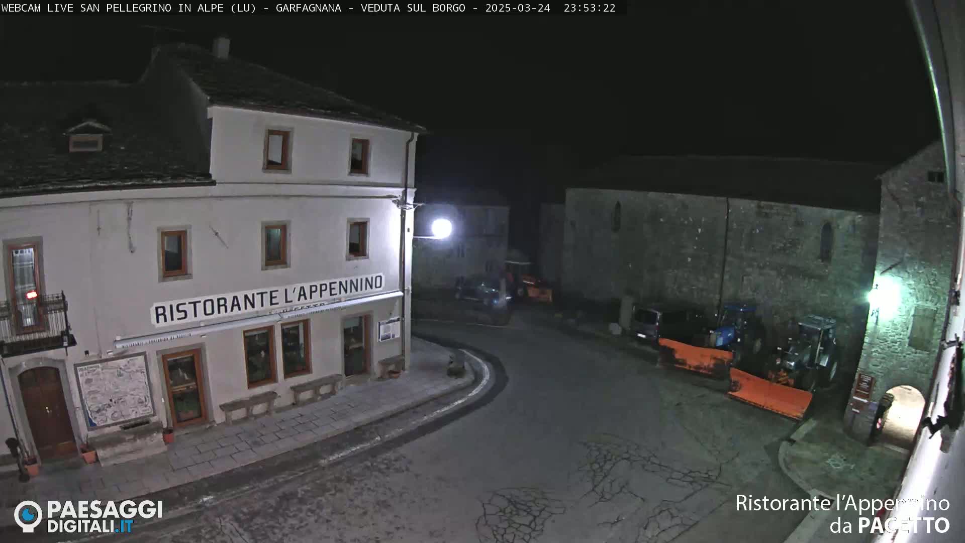 A nighttime, snow-covered street scene shows a restaurant called Ristorante L'Appennino and several parked vehicles, including what appear to be snowplows.