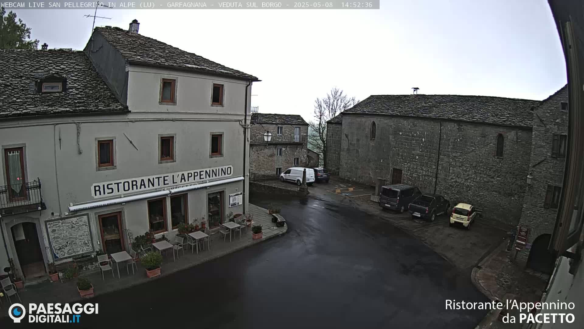 A wet town square is seen, with several parked cars and a restaurant named "Ristorante l'Appennino" visible; older stone buildings surround the square.