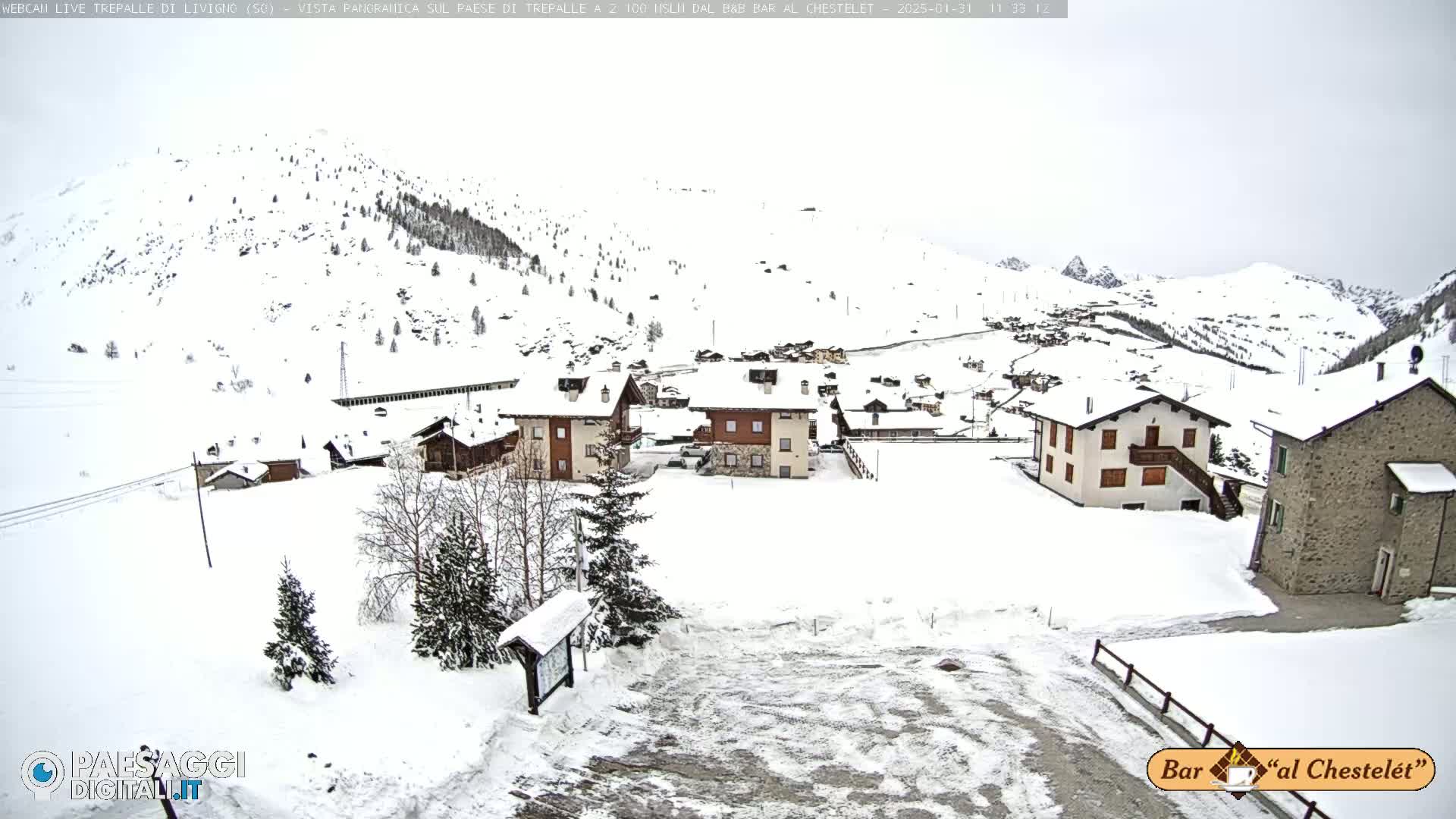 A snow-covered village nestled in a mountainous region under an overcast sky.